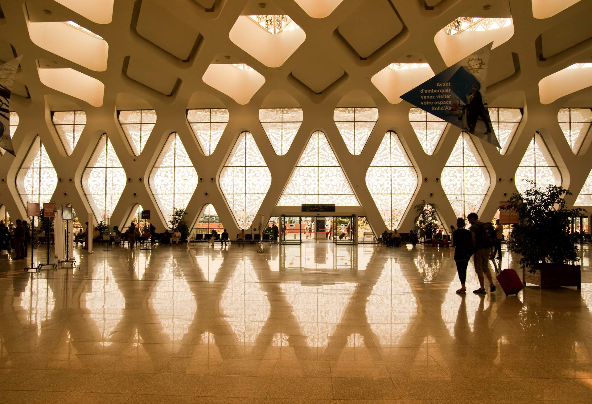 marrakech airport architecture reflection light couple suitcase travel travelling departure walking baggage africa windows entrance floor people person travel trip tour route holidays vacations adventure shape