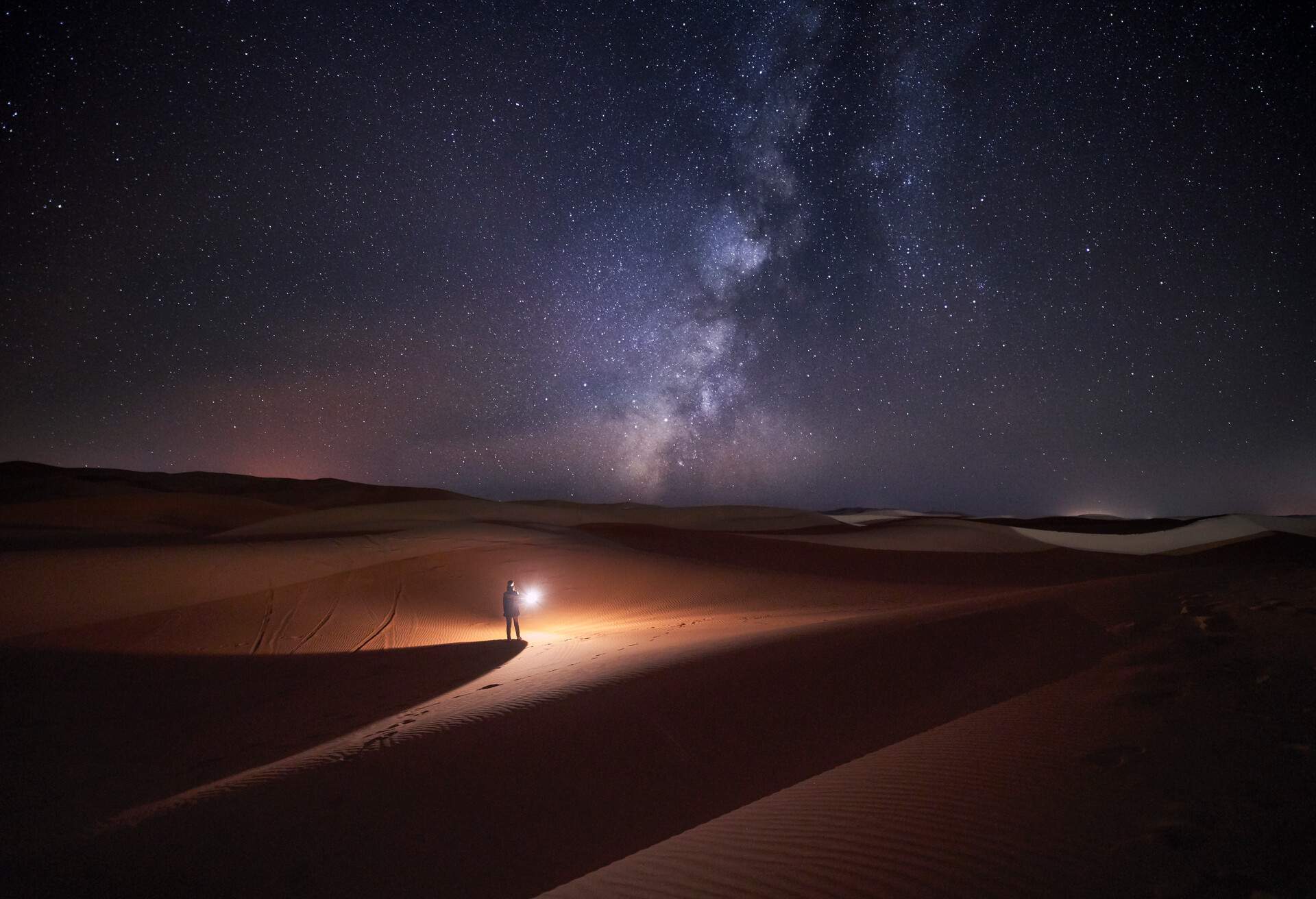 DEST_MOROCCO_MERZOUGA_DESERT_PERSON_NIGHT_SKY_GettyImages-1147346778