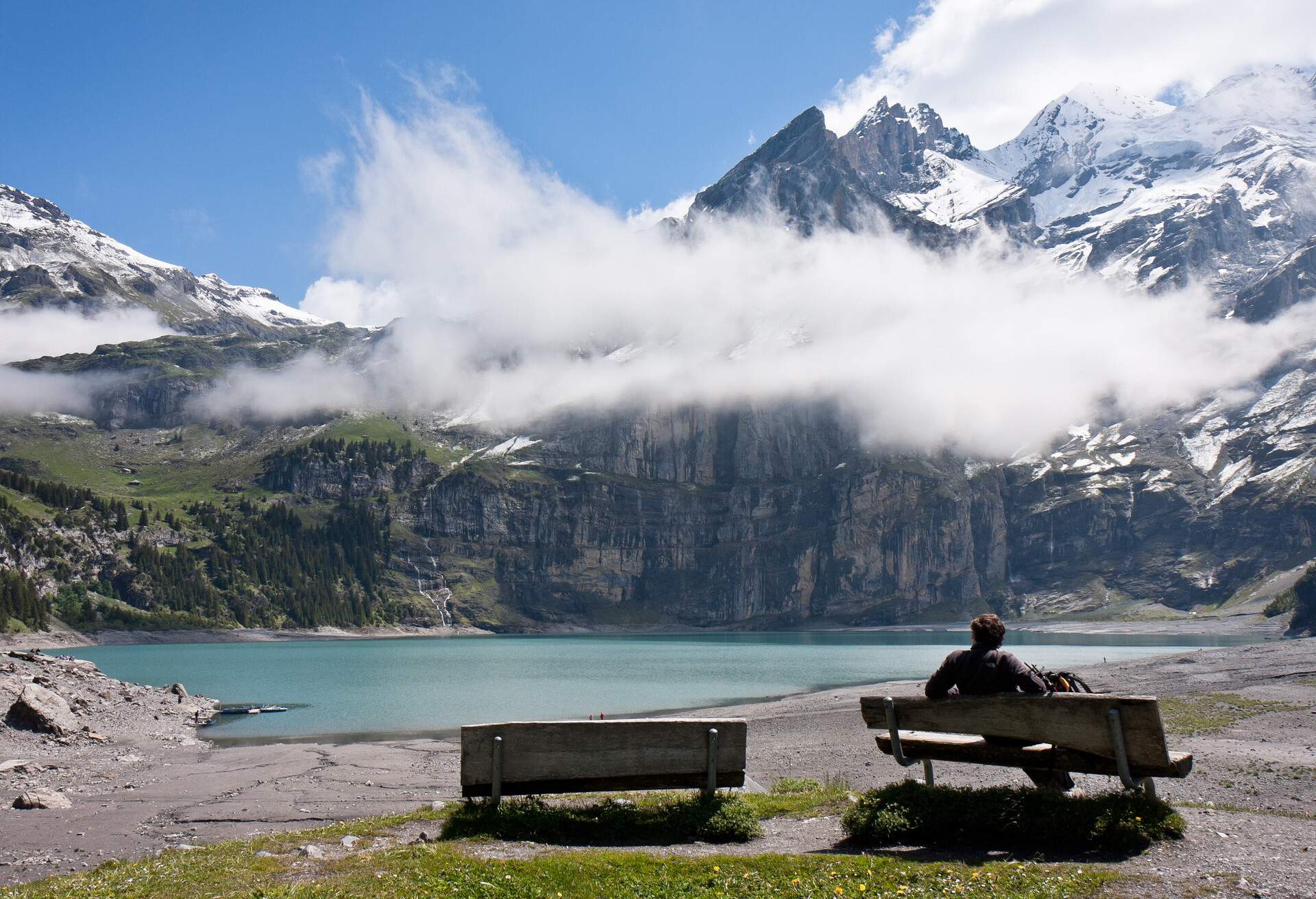 Man relaxing in front of spectacular view of Swiss lakes and mountains, Lake Oeschinen, Switzerland.