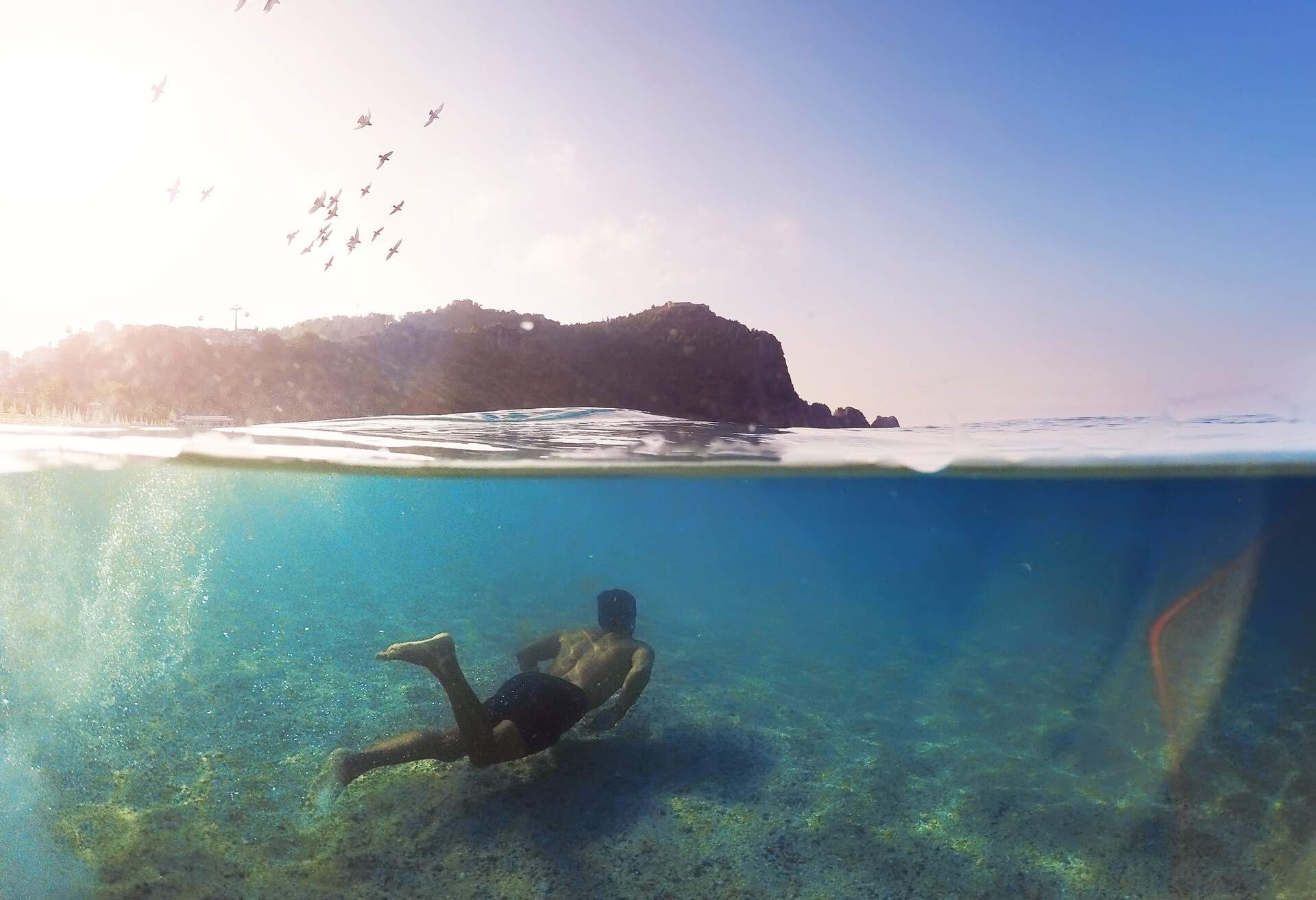 Young man swimming underwater in Alanya, Antalya. Cleopatra beach near Alanya castle. Birds are flying. Photo taken with gopro hero 4 and dome.