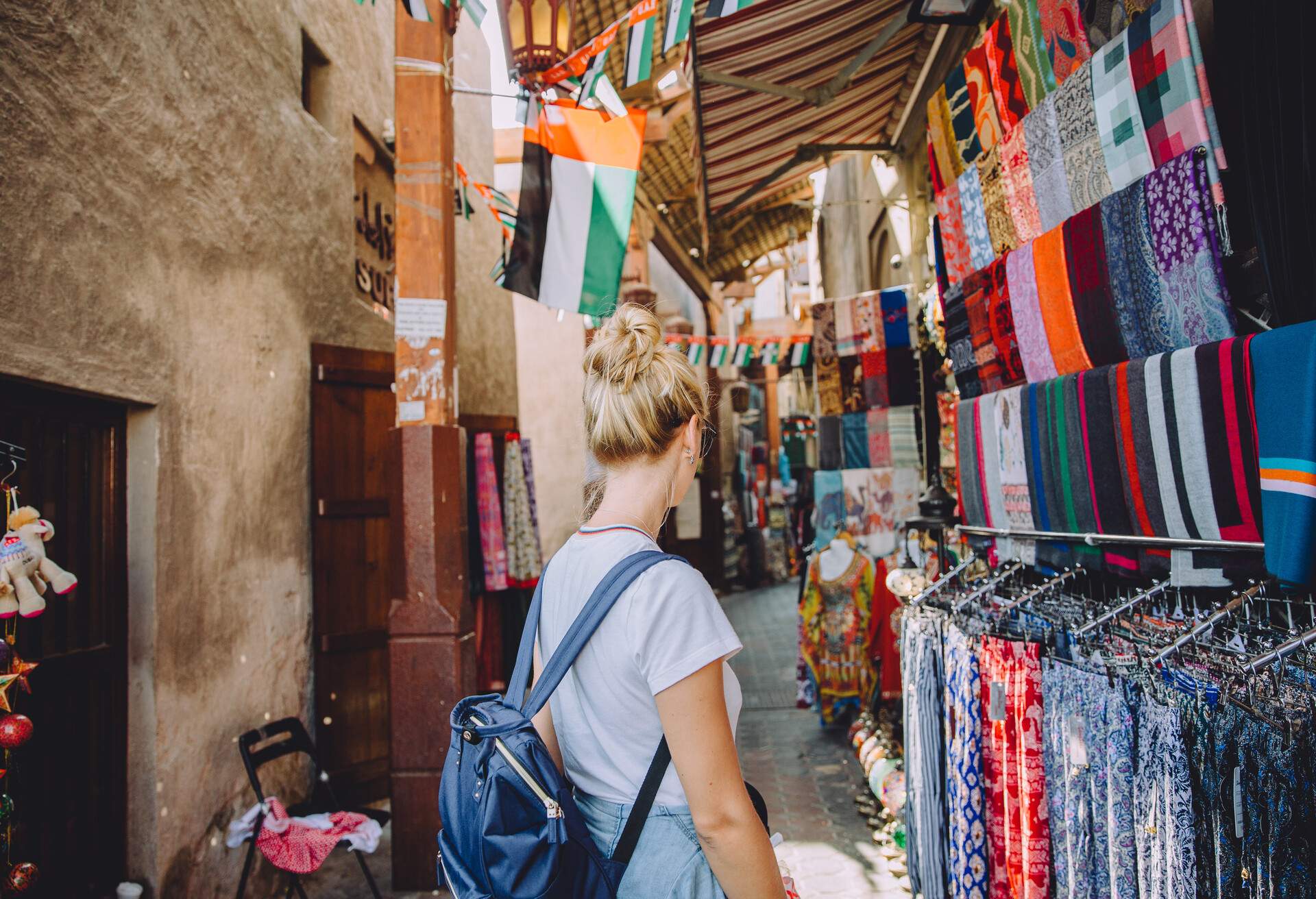 Back view of young female traveller at traditional bazaar in Dubai, UAE; Shutterstock ID 1103214140