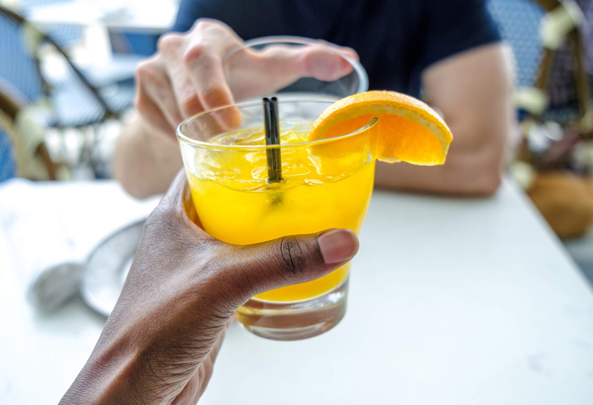 Close-up of unrecognizable woman and man holding up their drinks in a toast