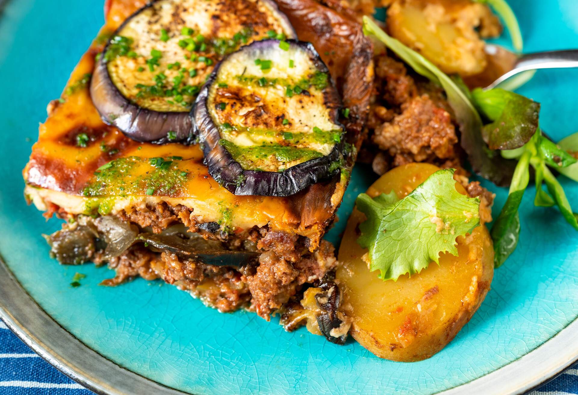 Detail of traditional greek moussaka on blue plate, closeup.