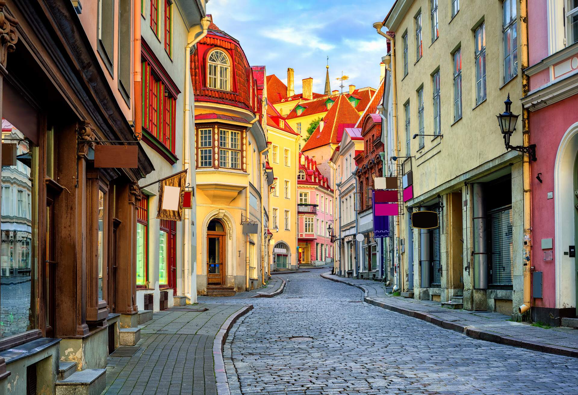 An empty, narrow street, paved with rustic bricks, is flanked by an array of colourful buildings, creating a peaceful yet vibrant urban landscape.