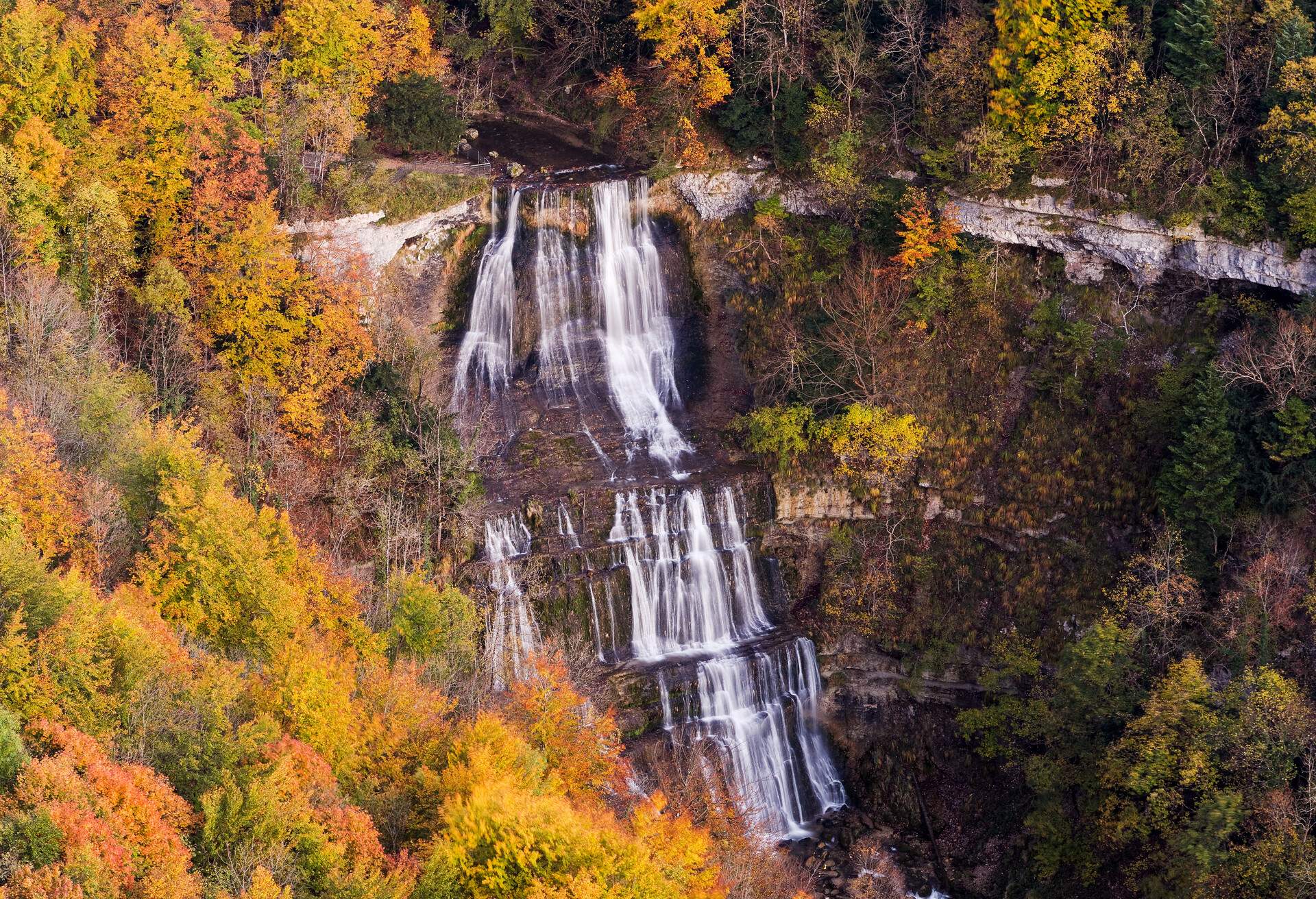 A low-volume waterfall surrounded by vibrant fall foliage.