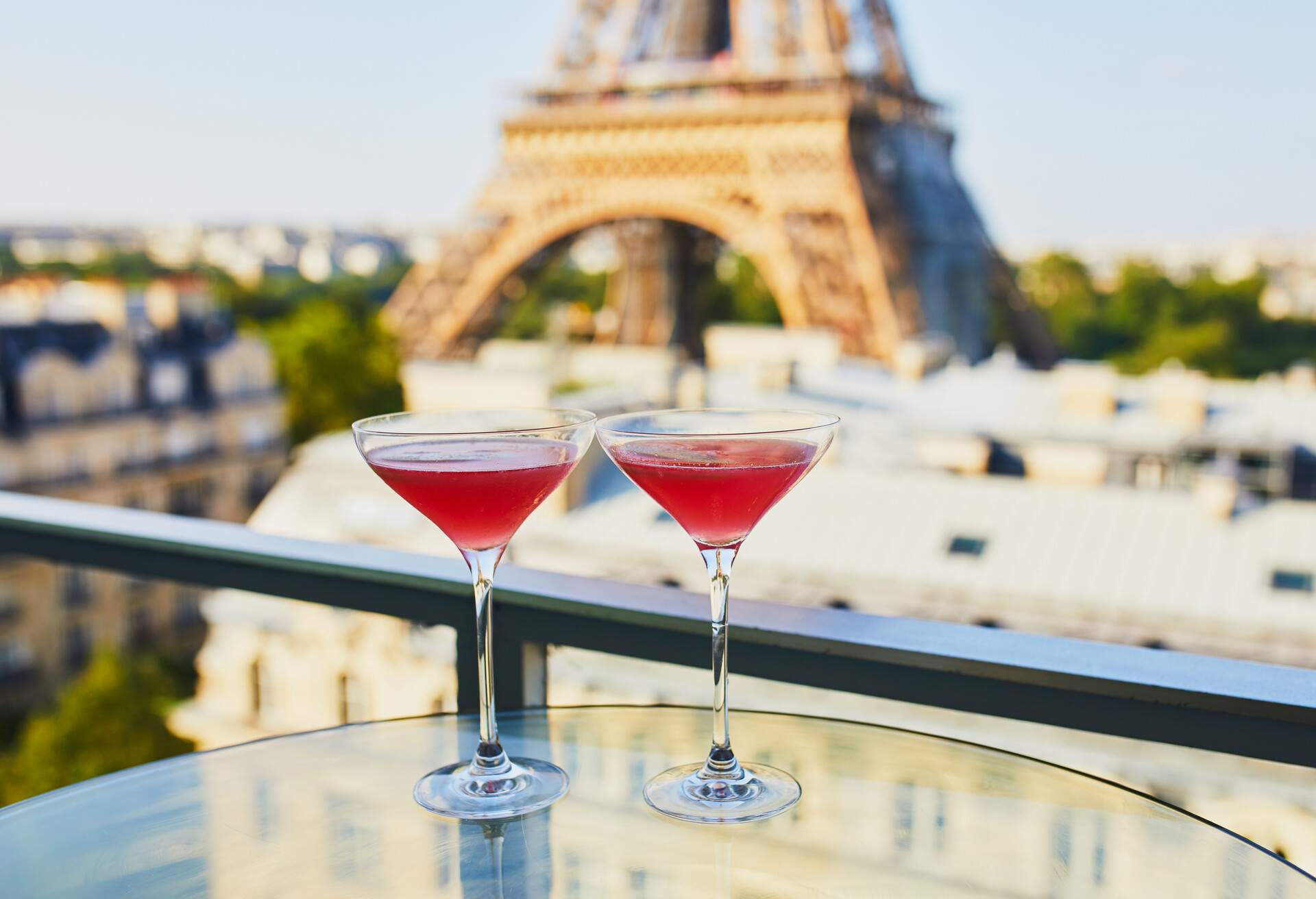 Two Cosmopolitan cocktails in traditional martini glasses on a glass table with view to the Eiffel tower, Paris, France