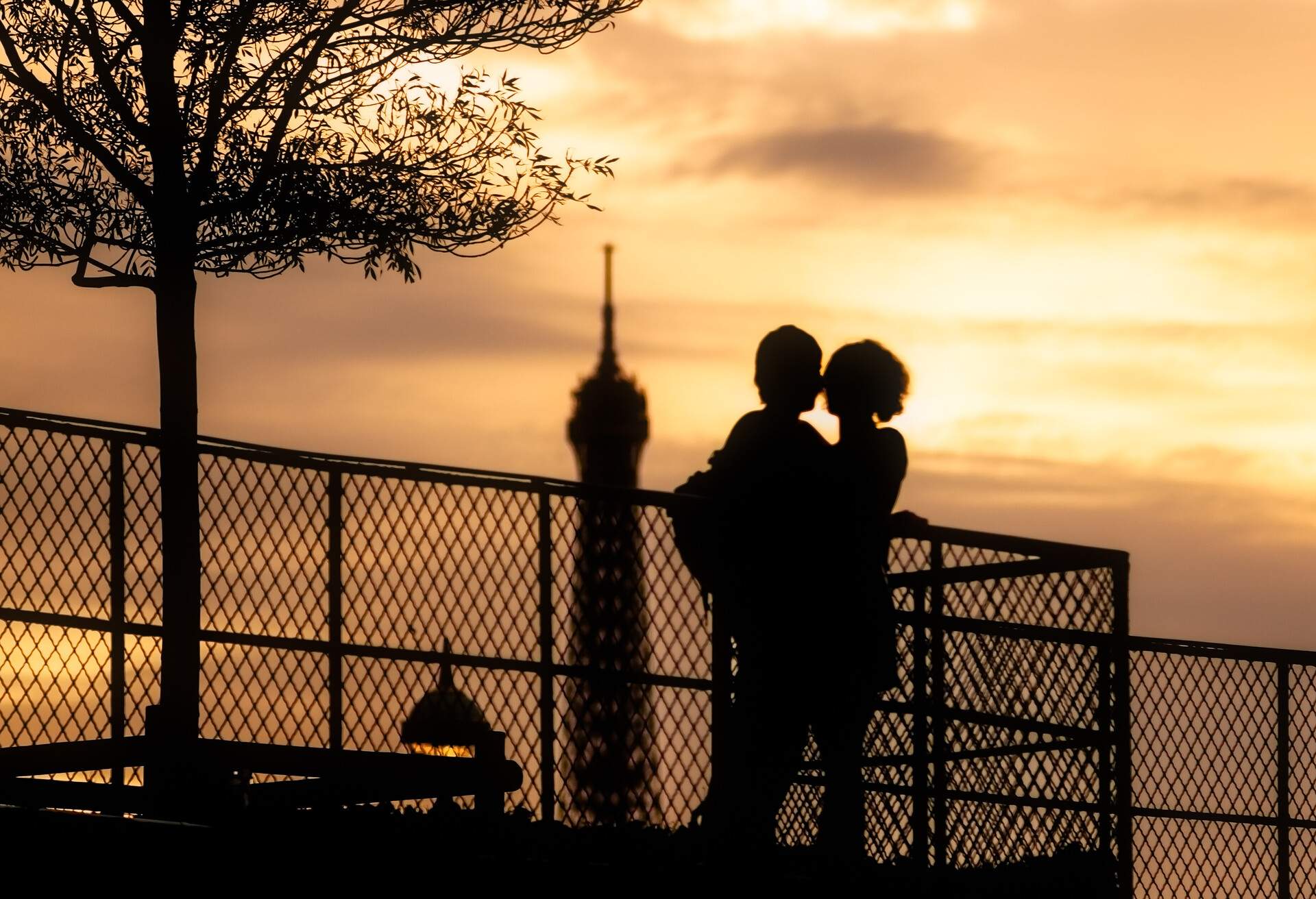 Young couple silhouette against sunset with the Eiffel tower in the background in Paris, France