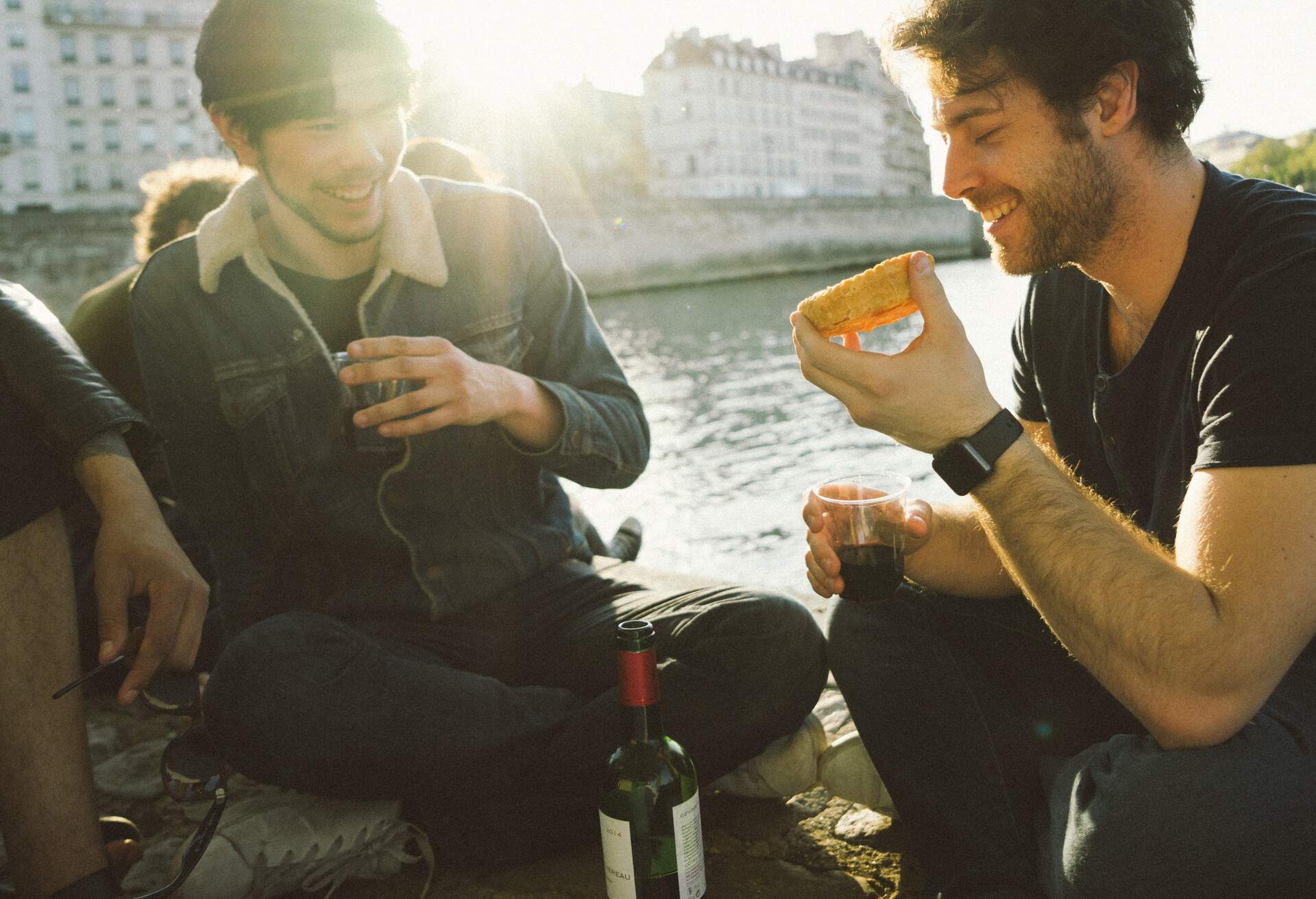 Group of friends having food and wine by the Senna river at sunset.