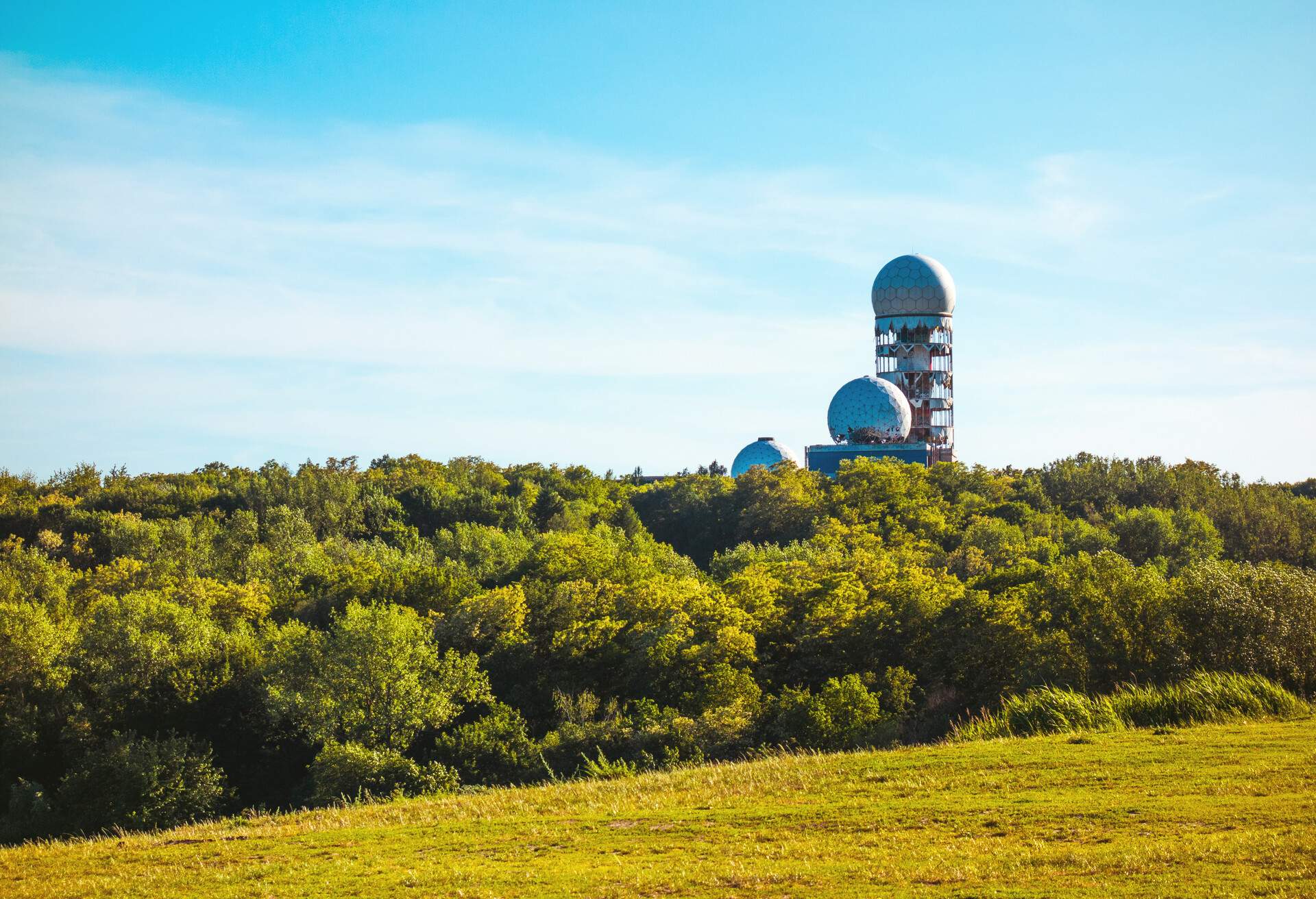 Derelict radomes in the lush forest mountain against the blue sky.
