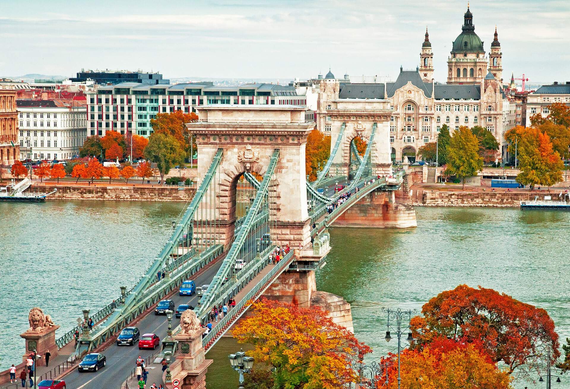 A chain bridge with lion sculptures in stone on each side of the bridge end.