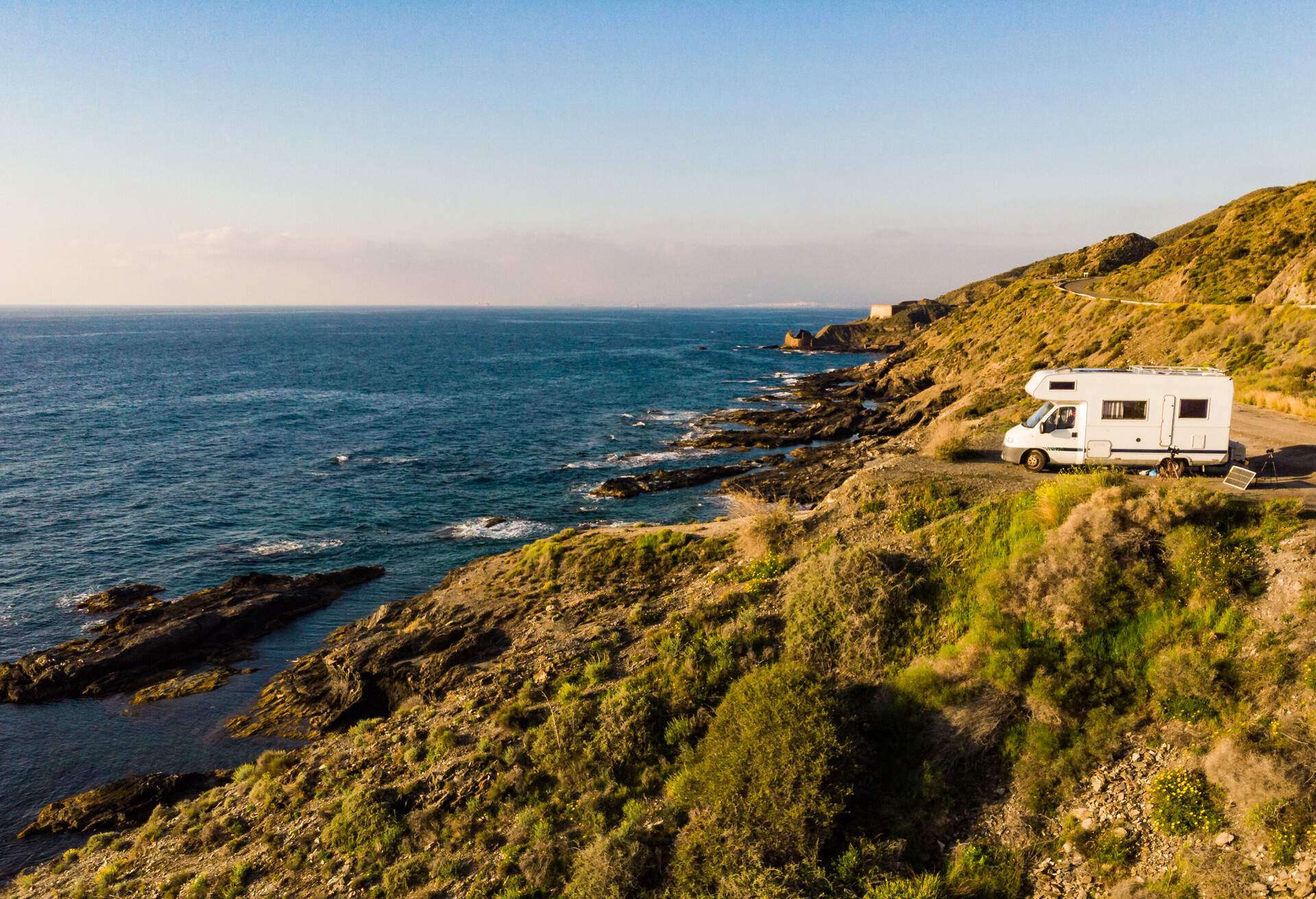 Spanish rocky coastline with camper car camping on cliff sea shore. Mediterranean region of Villaricos, Almeria, eastern Andalusia, Spain. 