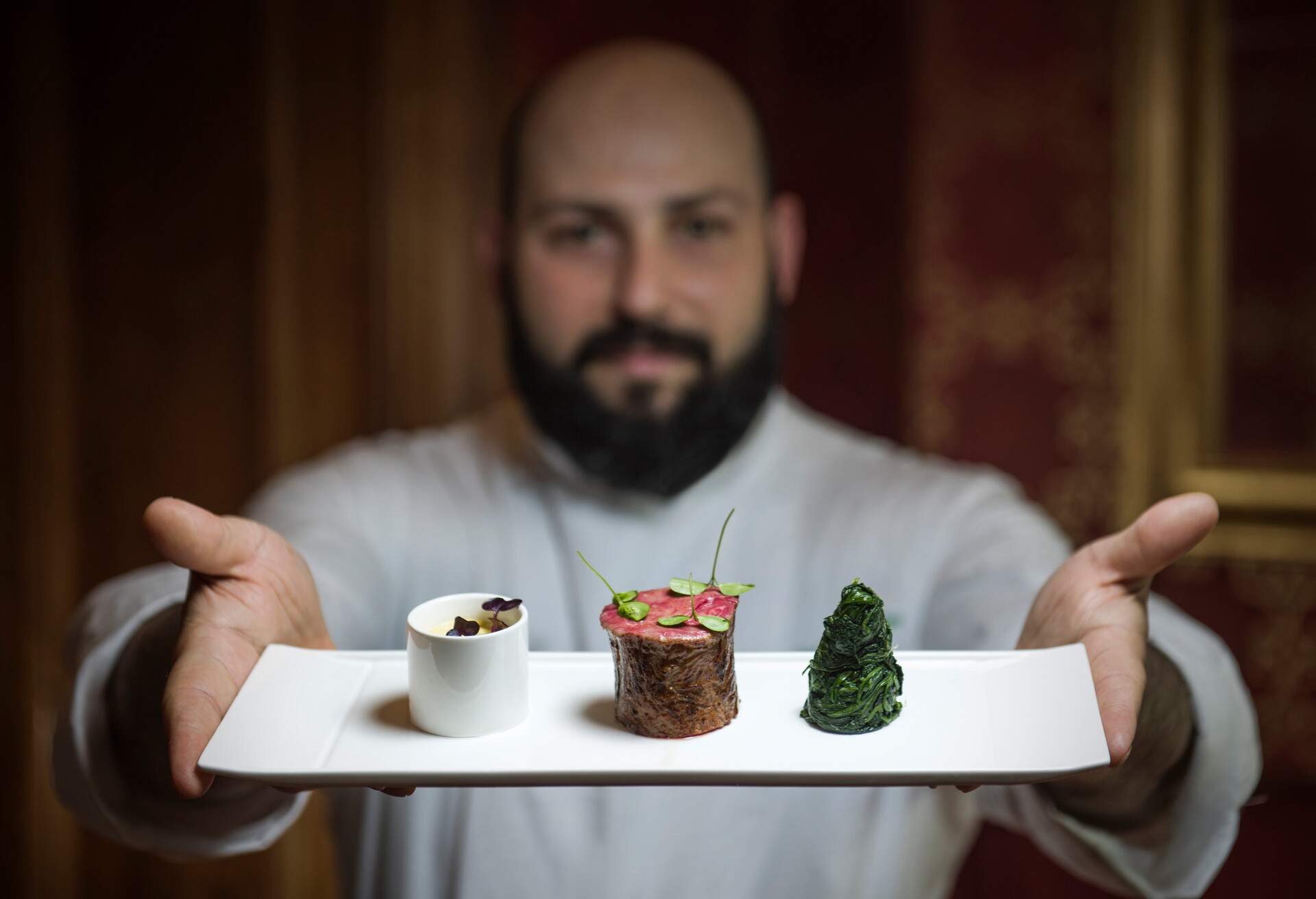 A male chef presenting a beautifully arranged food.