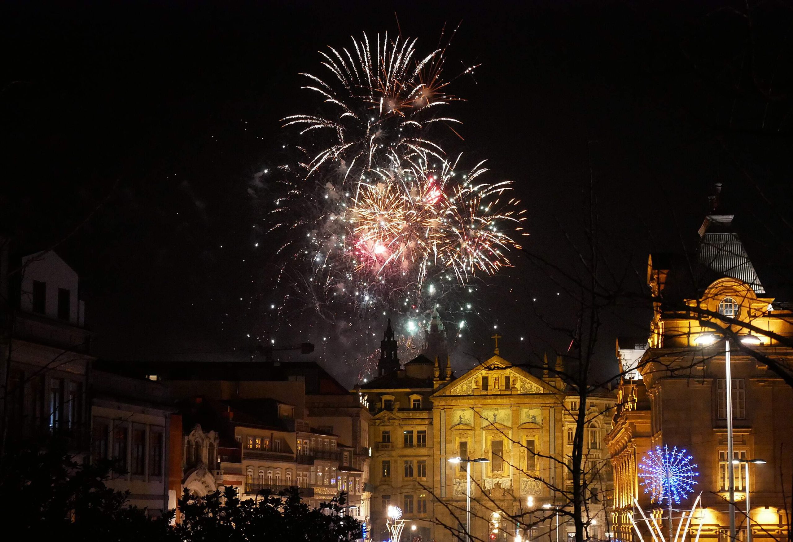 A dazzling display of fireworks exploding in the night sky above a city with lit buildings.