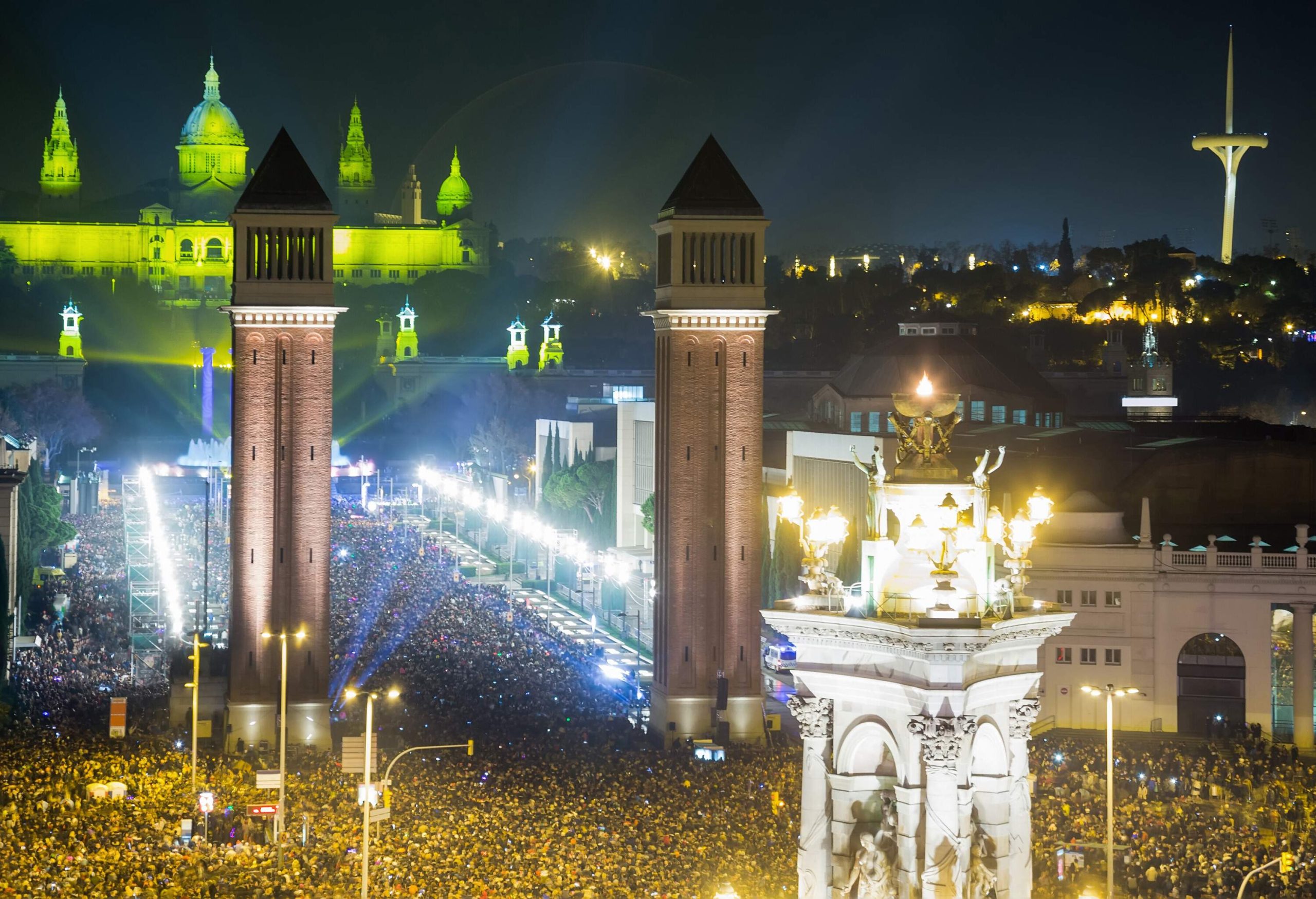 Crowds of people on a plaza with the Venetian Towers and illuminated buildings in the sight.