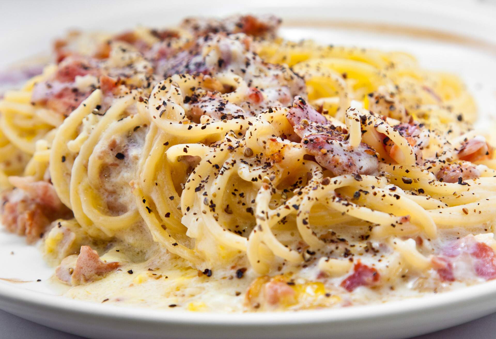 Spaghetti, bacon, white sauce, black pepper.