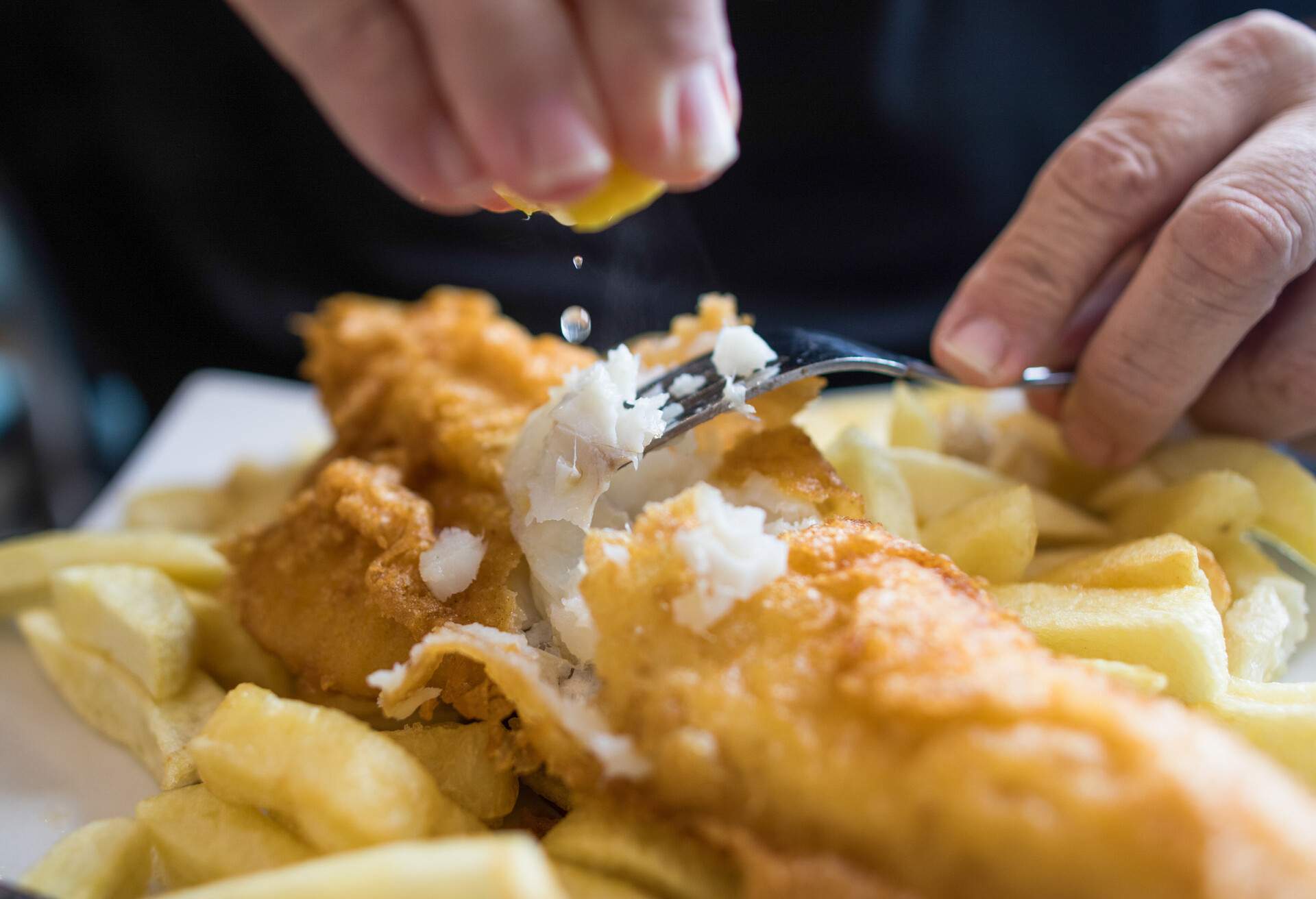 A customer squeezes a lemon over a cod and chips. Photographer: Chris Ratcliffe/Bloomberg