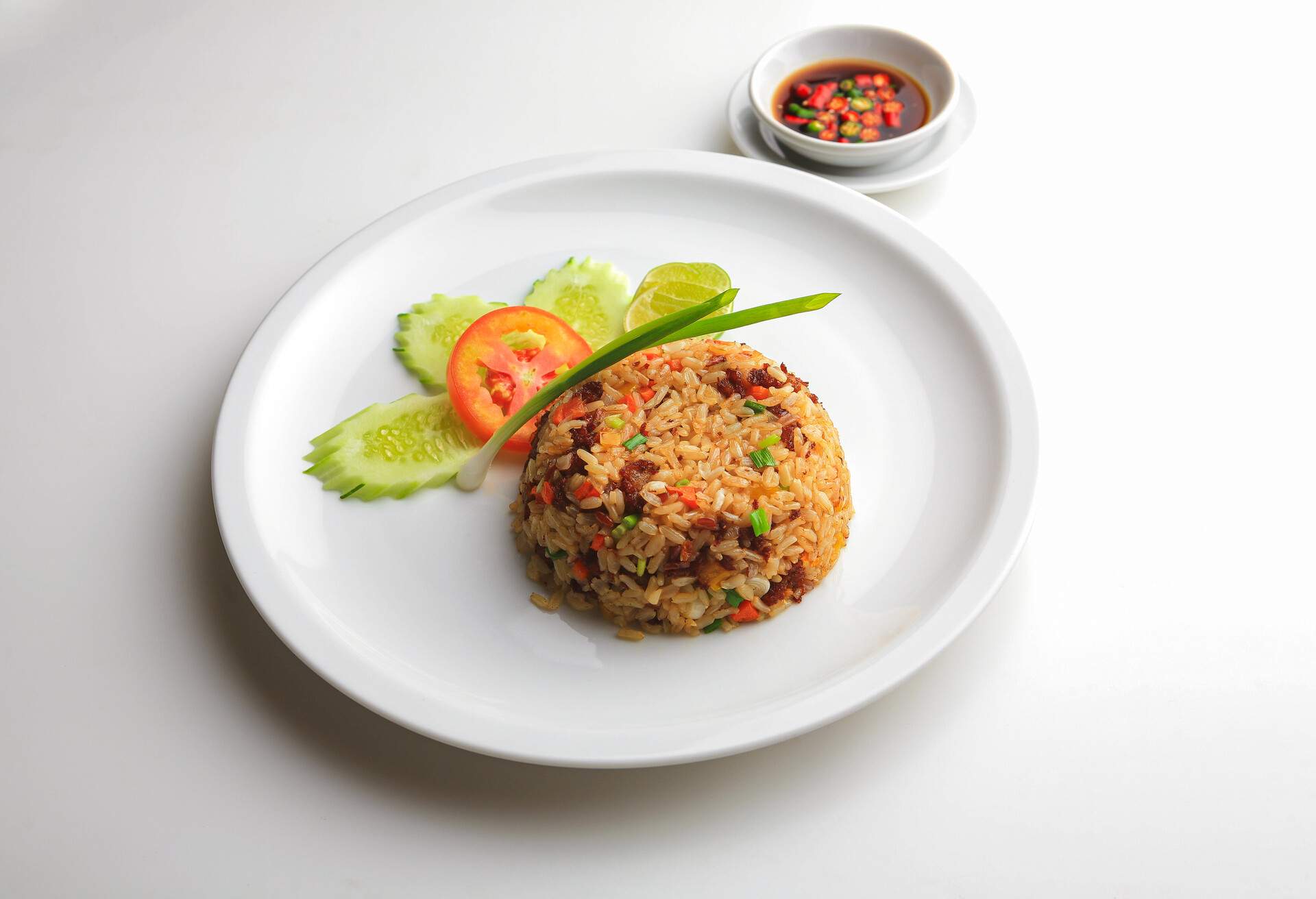 Above view of Asian fried rice with egg and vegetable in white ceramic plate on the table in the restaurant. Khao Pad popular traditional Thai style food. Top-down