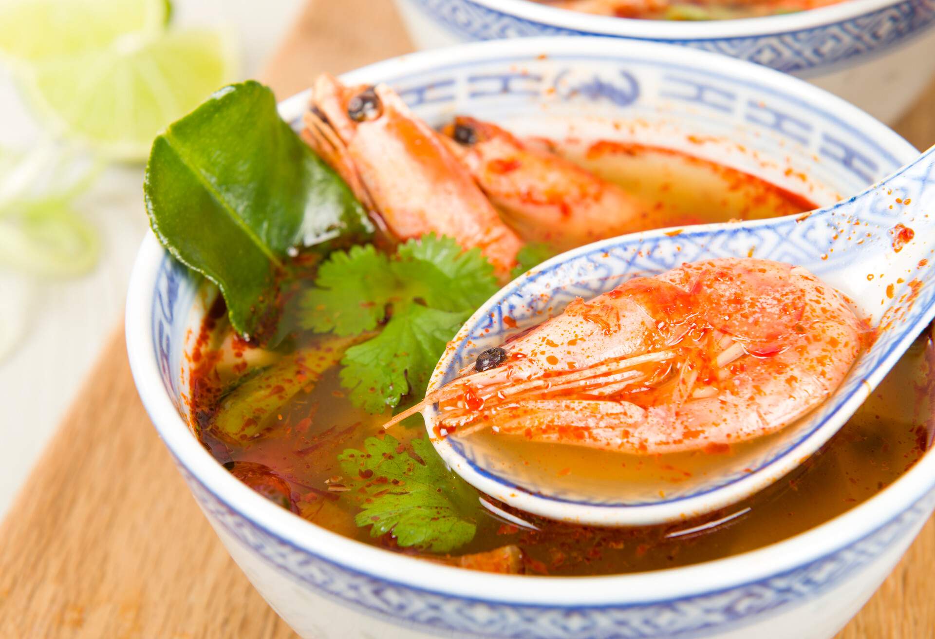 Thai hot and sour soup with king prawns and oyster mushrooms served with lime wedges.