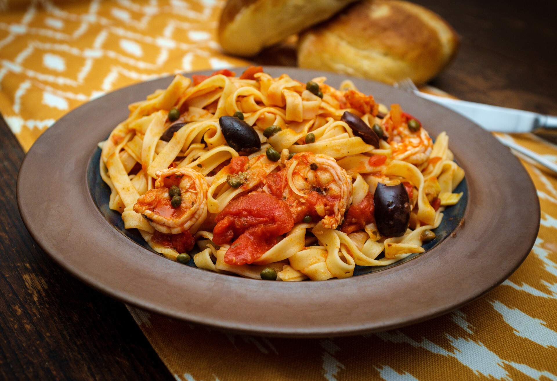 Delicious Spaghetti alla puttanesca with jumbo shrimp and fresh italian bread