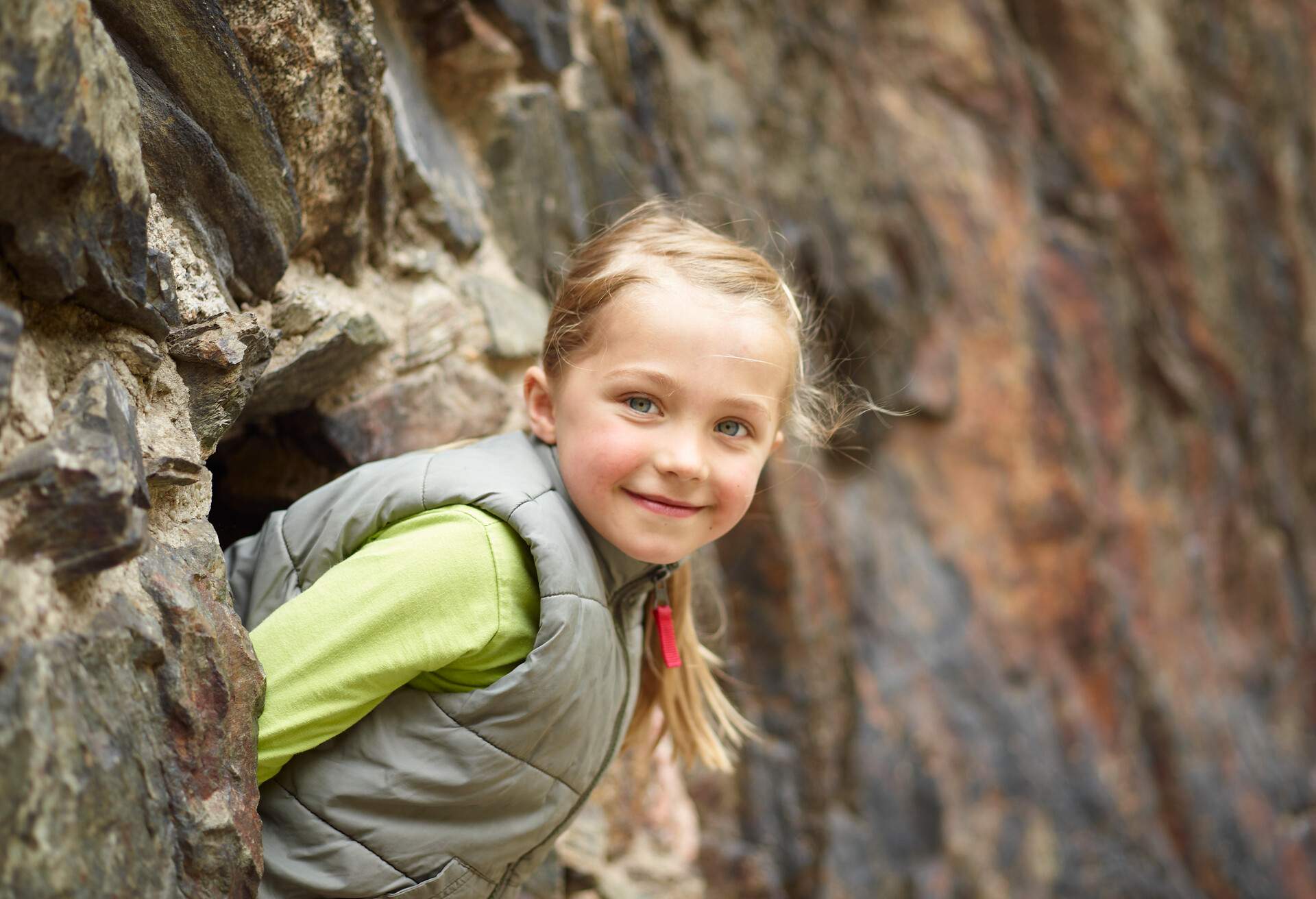Girl smiling while looking out from cave in mountain.