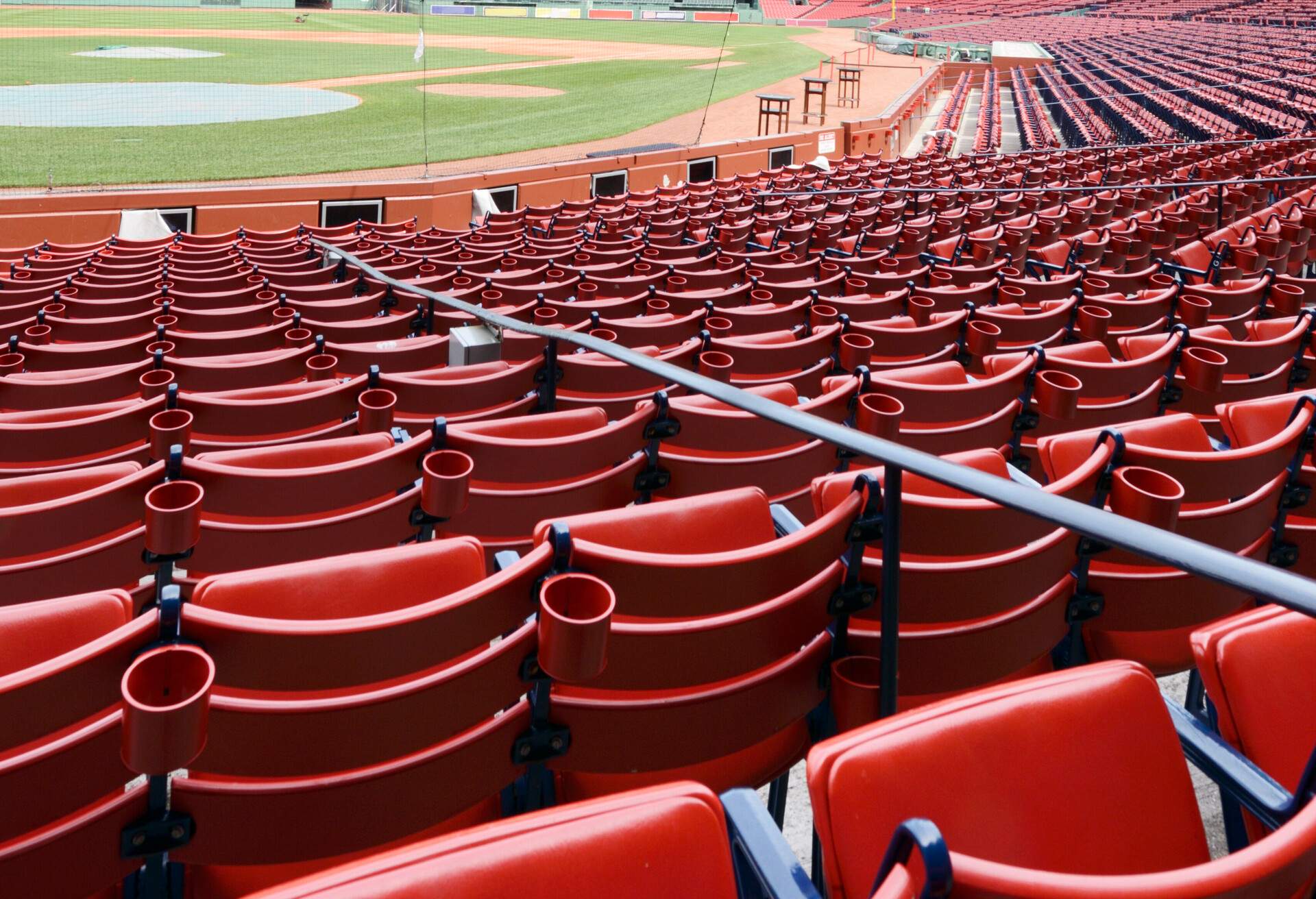 Empty red benches lined per row in a baseball stadium.