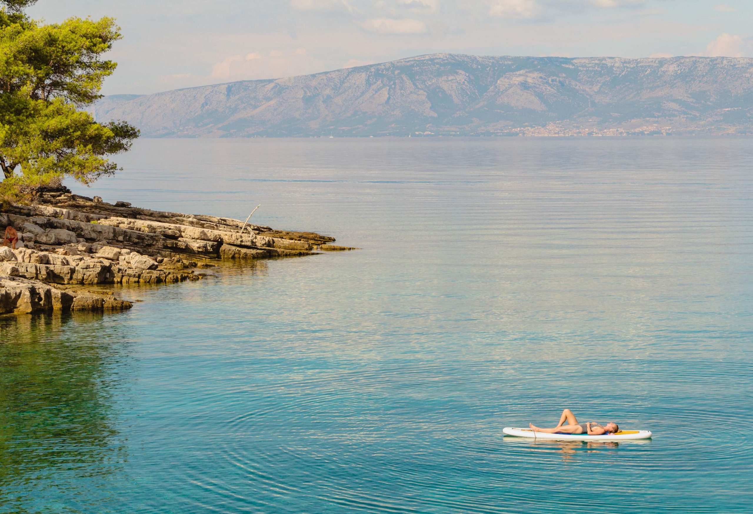 A woman lying on a paddleboard floating in the sea.