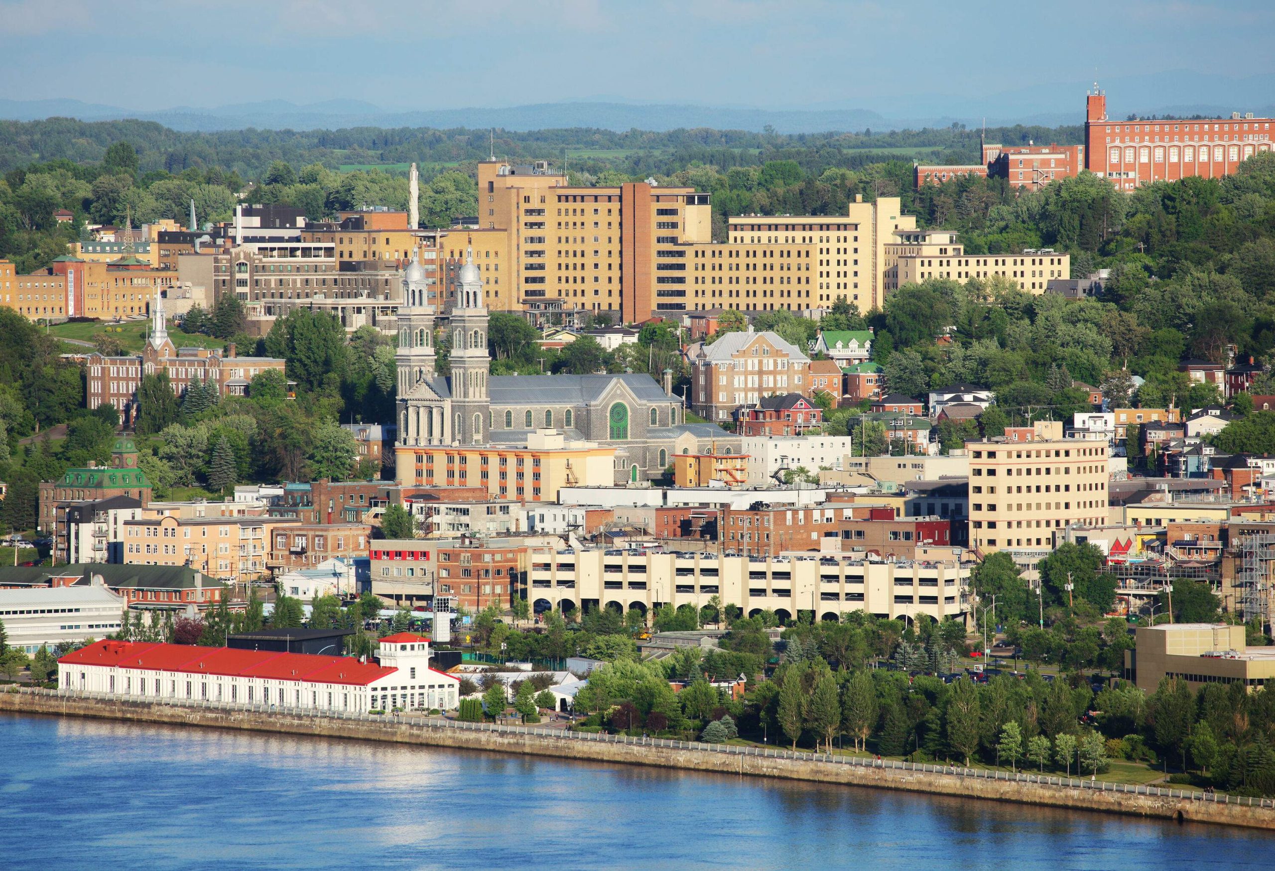 A town by the river filled with French Colonial-style buildings among trees.