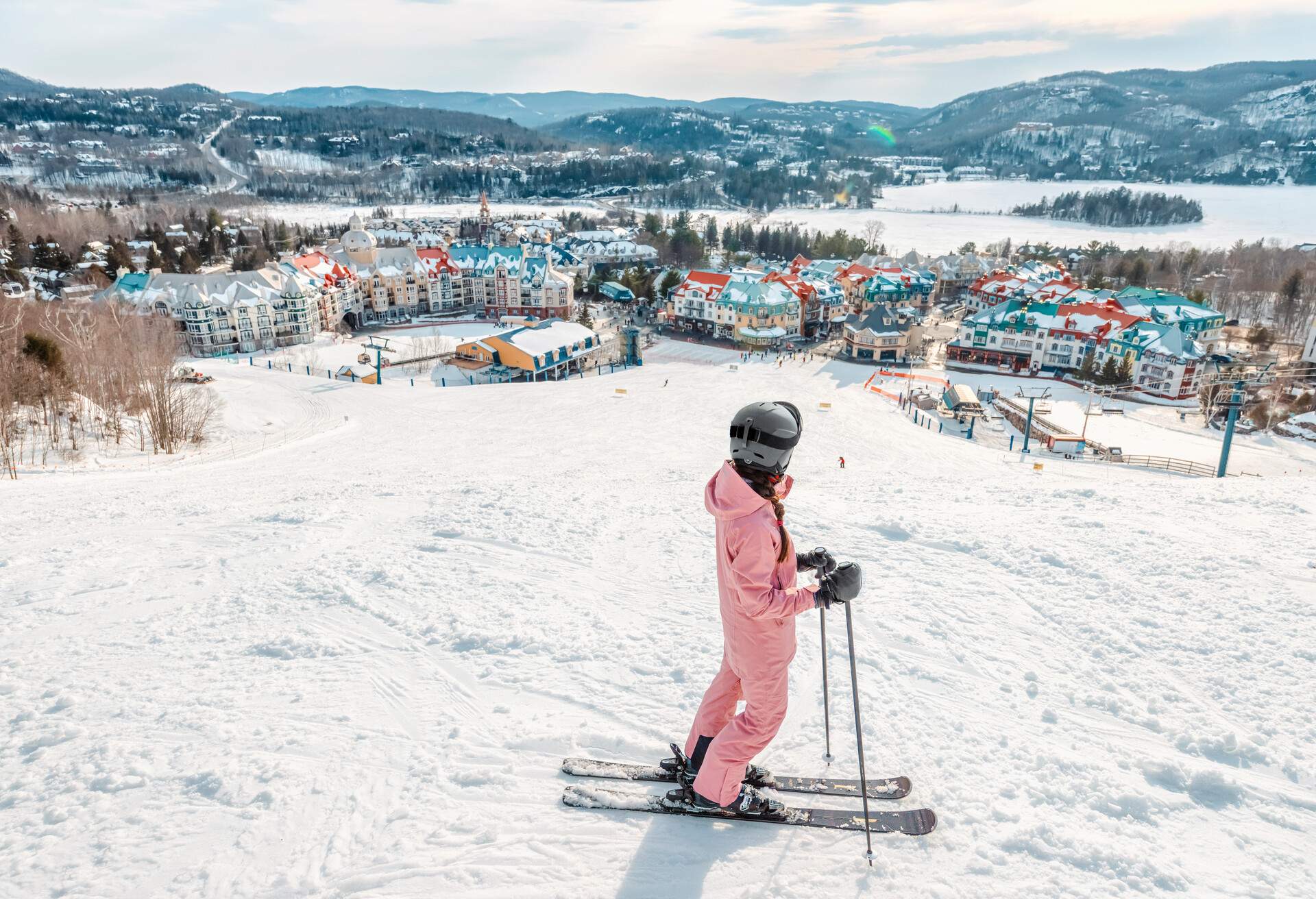 Skiing woman. Alpine ski - skier looking mountain village ski resort view starting skiing downhill on snow covered ski trail slope in winter. Mont Tremblant, Quebec, Canada.