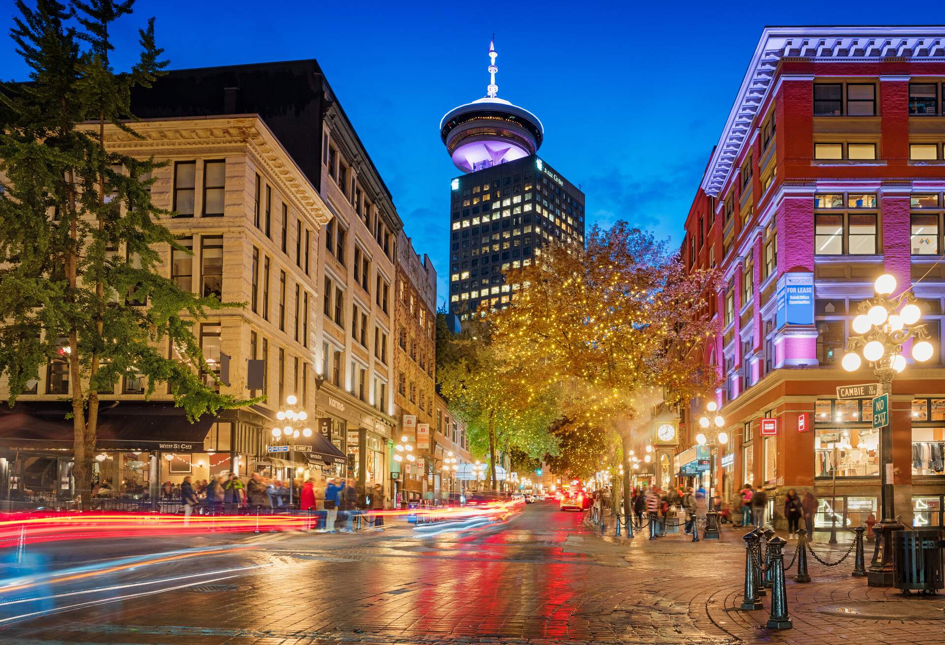 Long exposure stock photograph of Water street with the steam clock and the Vancouver Lookout in the background in Gastown, downtown Vancouver, British Columbia, Canada at twilight.