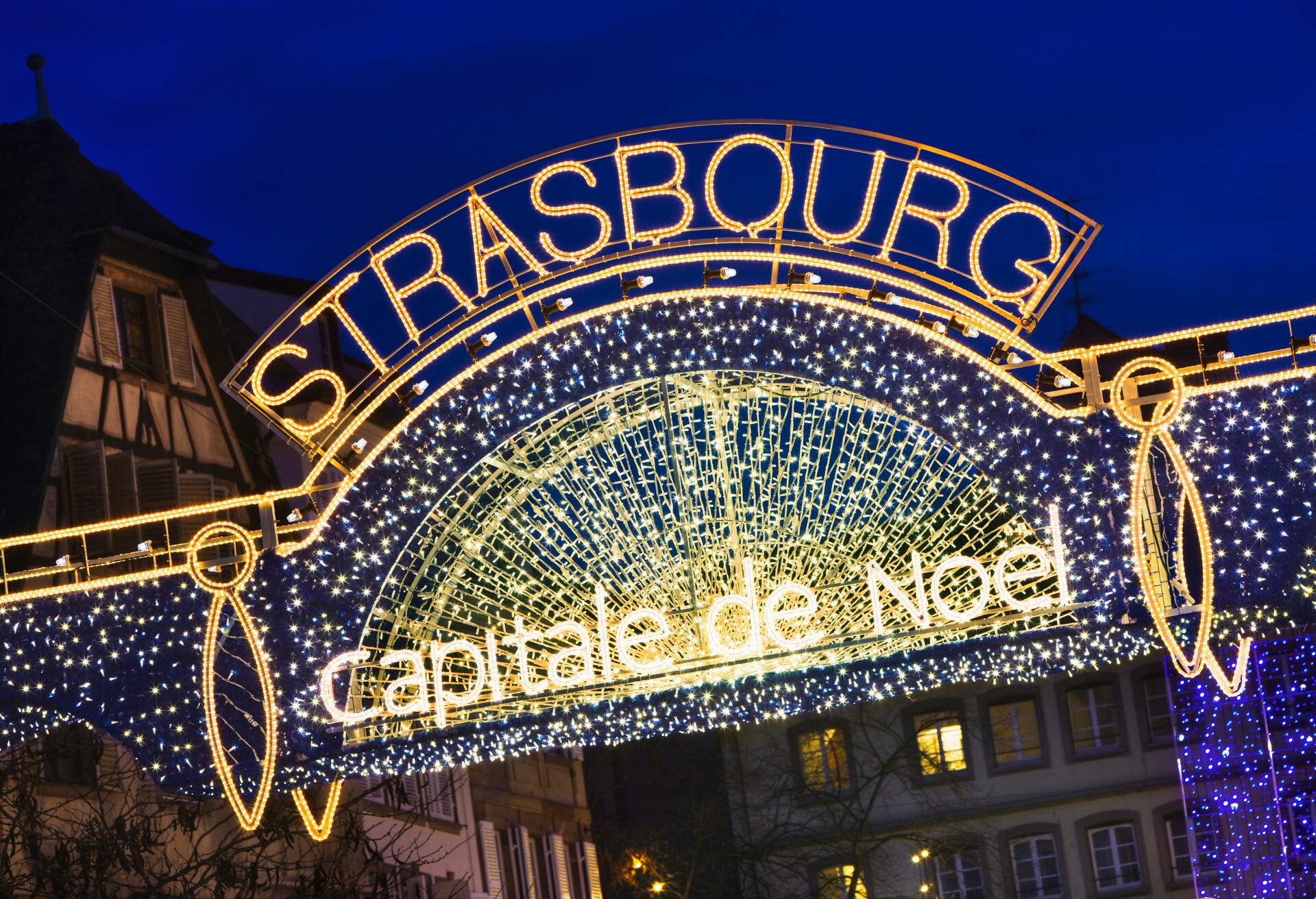 An entrance arch of a Christmas market decorated with string lights.