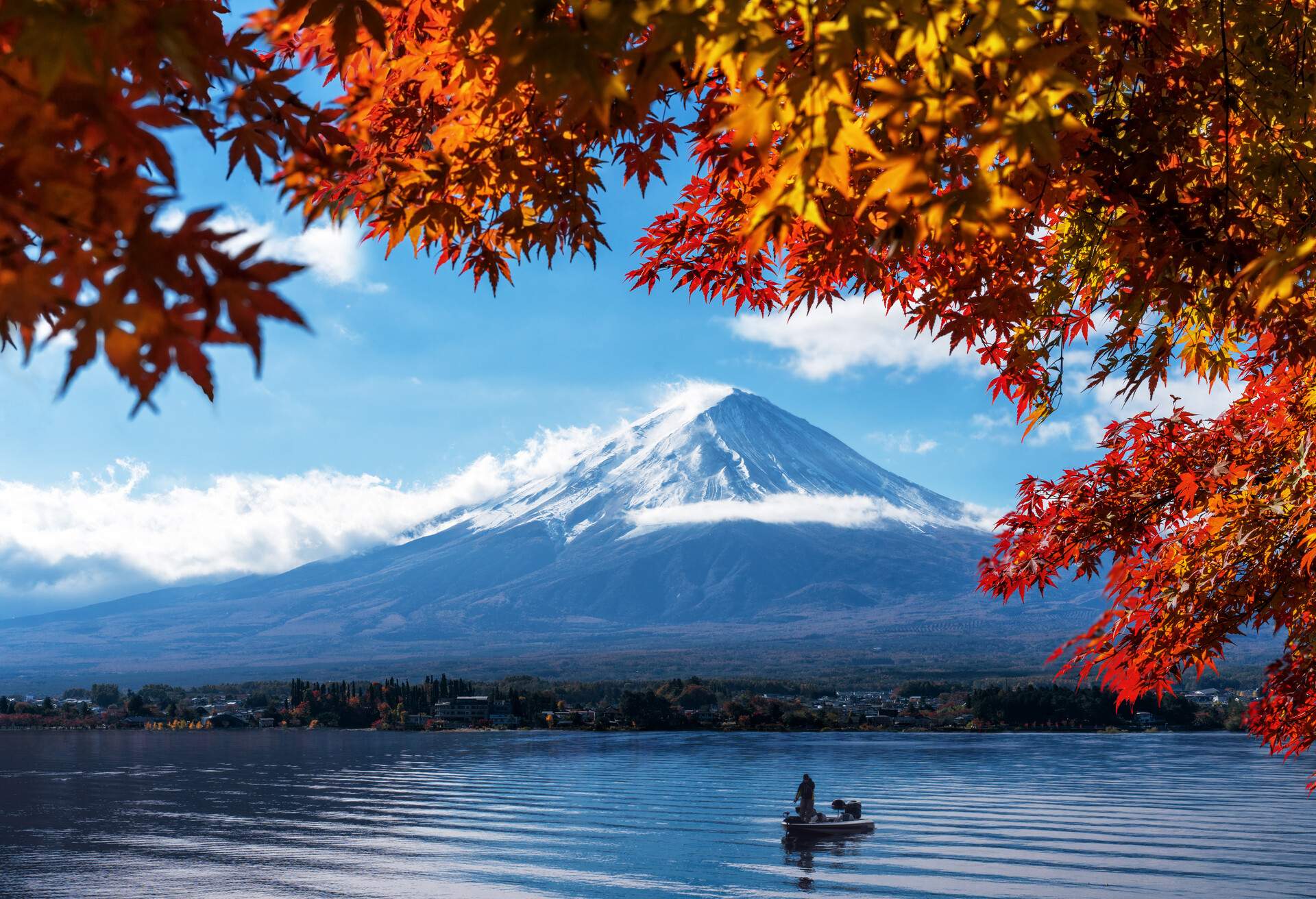 A boat on the lake overlooking the lakeside town and snow-capped Mount Fuji.