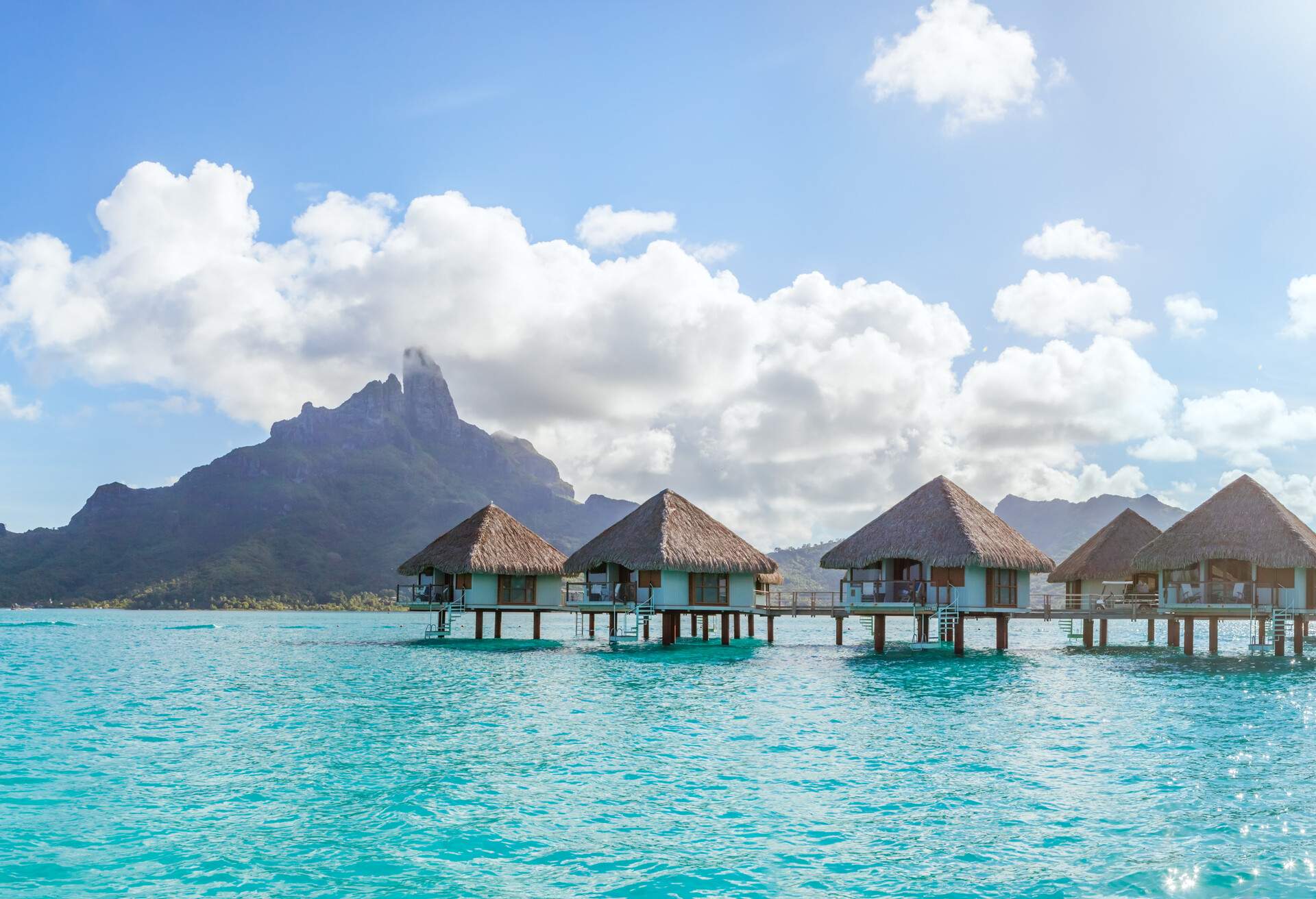 Overwater bungalows in the lagoon of Bora Bora, with Mt Otemanu in the background. Society islands, French Polynesia, Pacific islands.