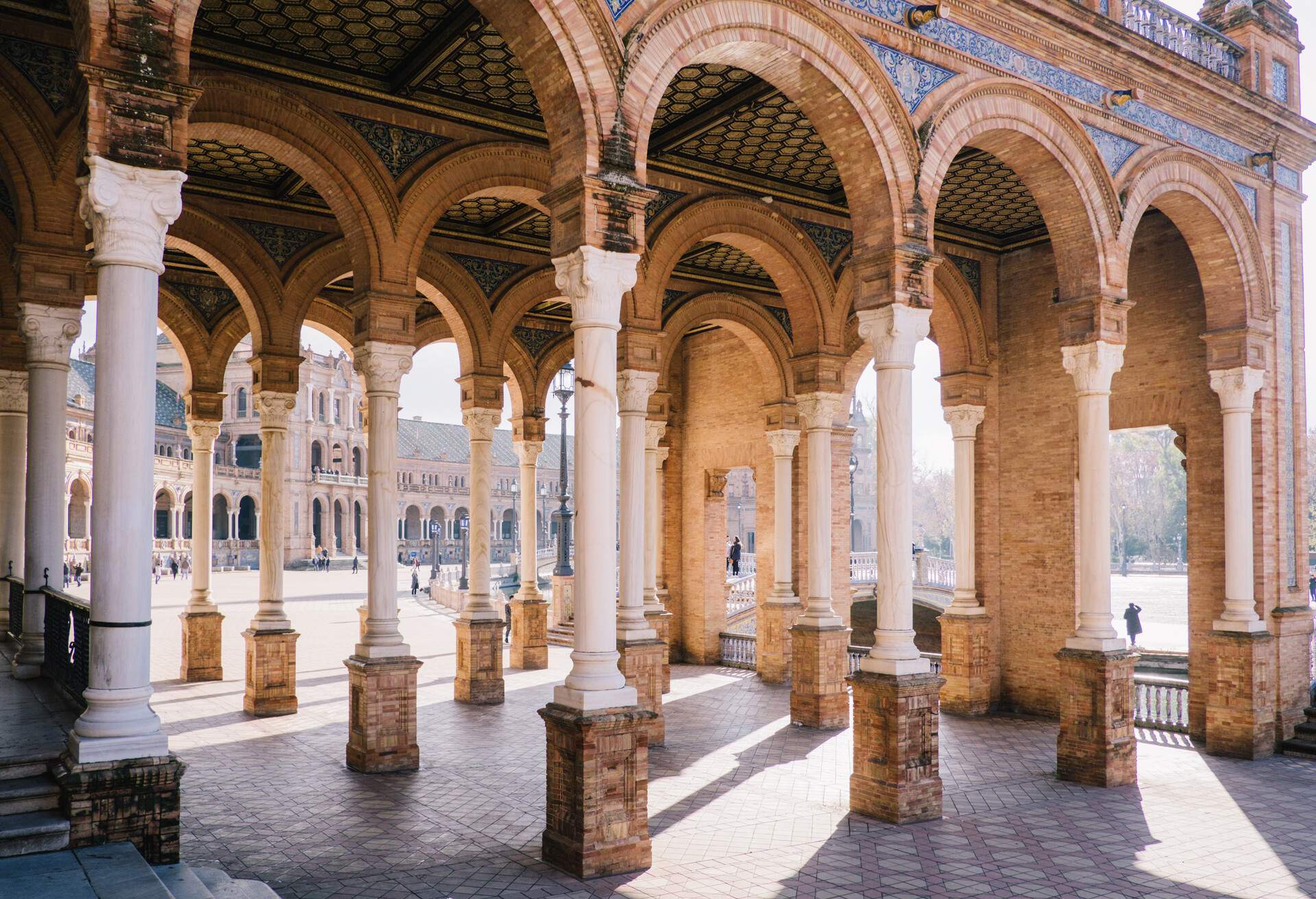 A series of arches supported by white columns in a town square.