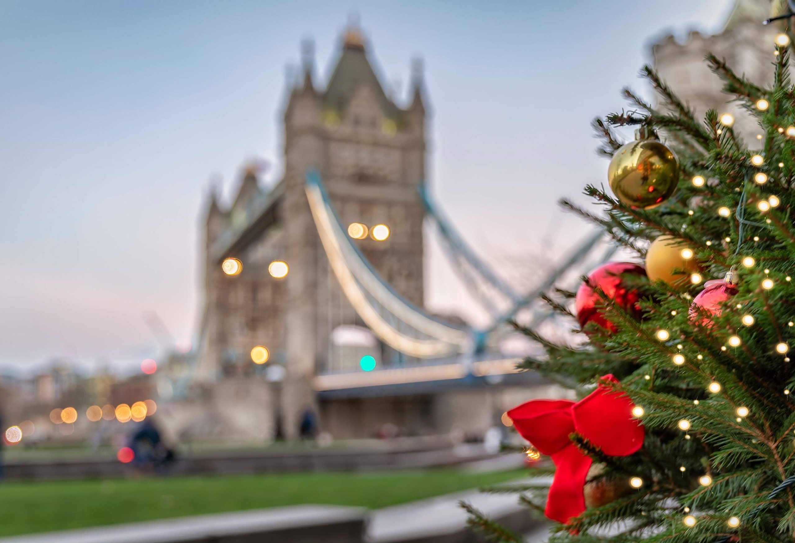 A Christmas tree decorated with colourful Christmas ornaments and a blurry image of London Bridge in the background.