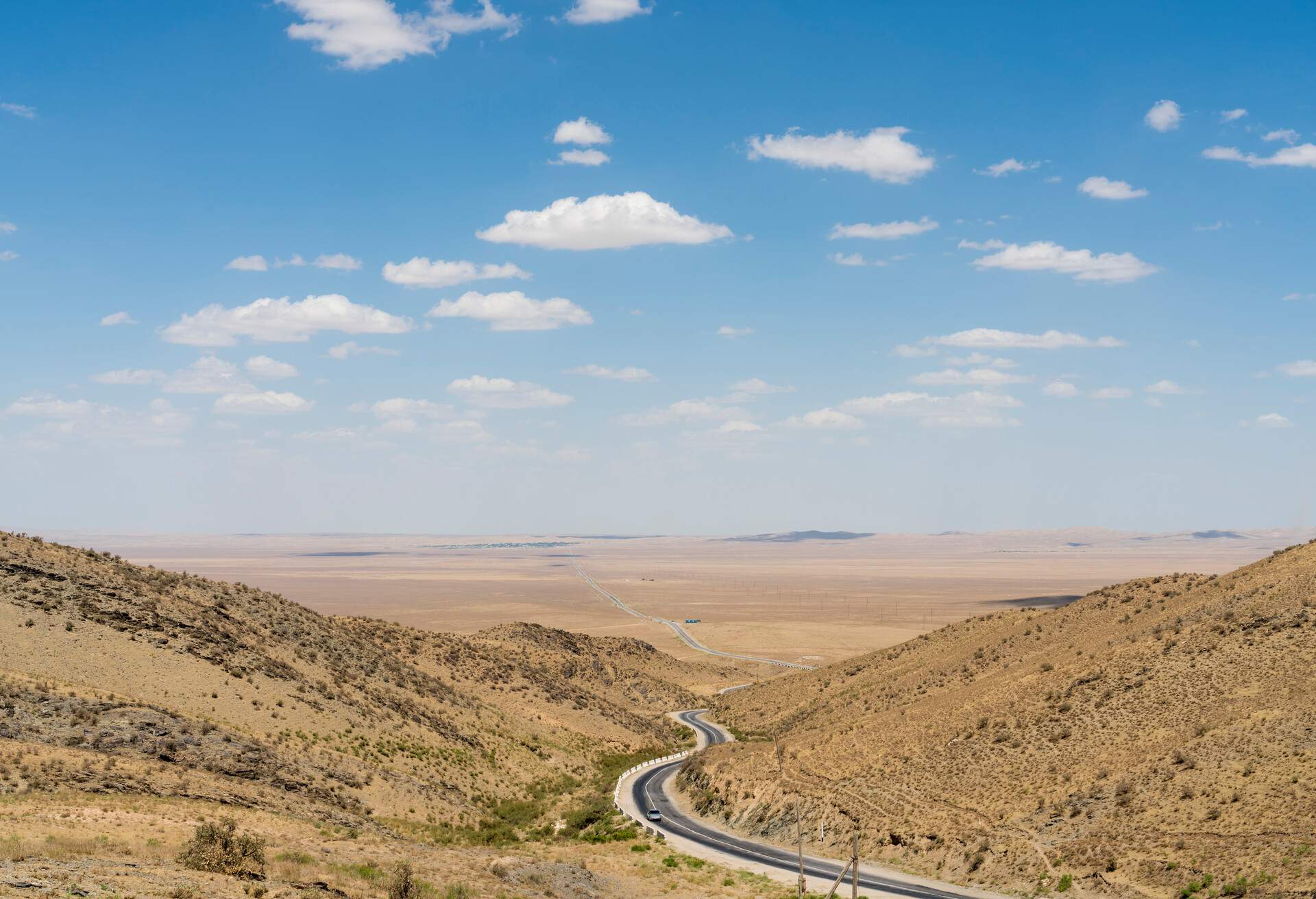 Long asphalt road in the desert against clear blue sky, diminishing perspective.