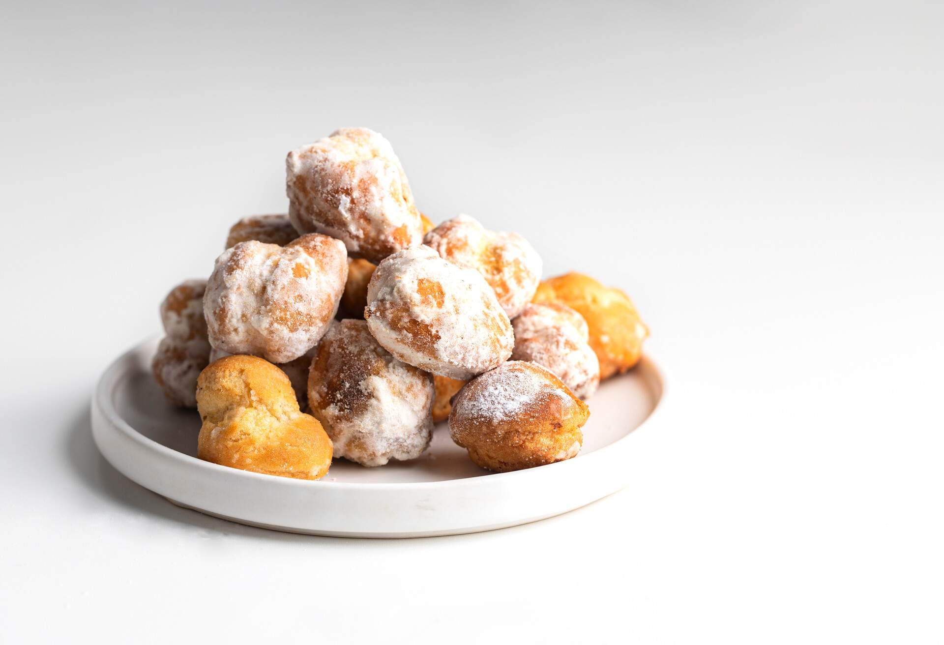 Small  deep fried doughs on trhe plate with sugar. Spanish Bonuelos de viento  background.