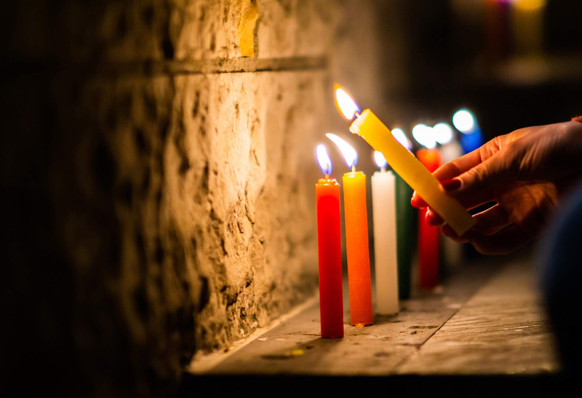 A woman's hand is seen, holding a lit candle to begin with the traditional day celebrated on December 7 called “Noche de Velitas”; Shutterstock ID 1552191821