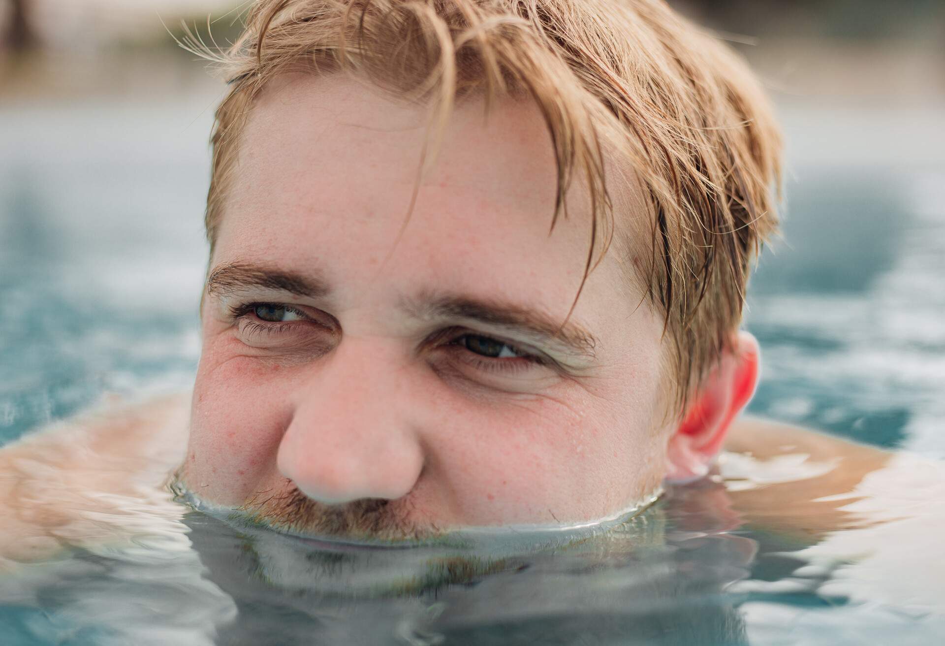Close up of happy handsome man swimming in a pool