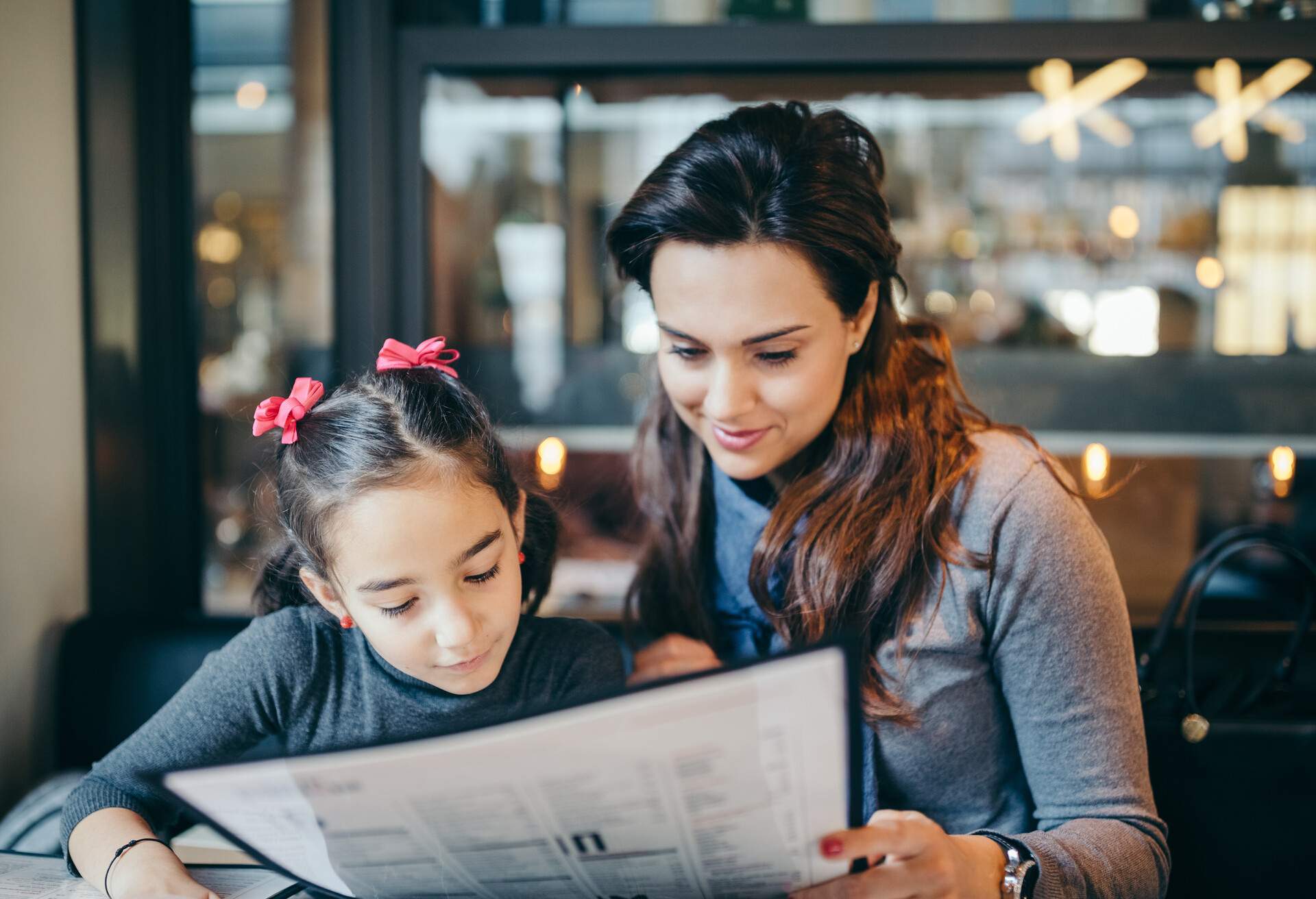 Mother and daughter reading the menu in restaurant
