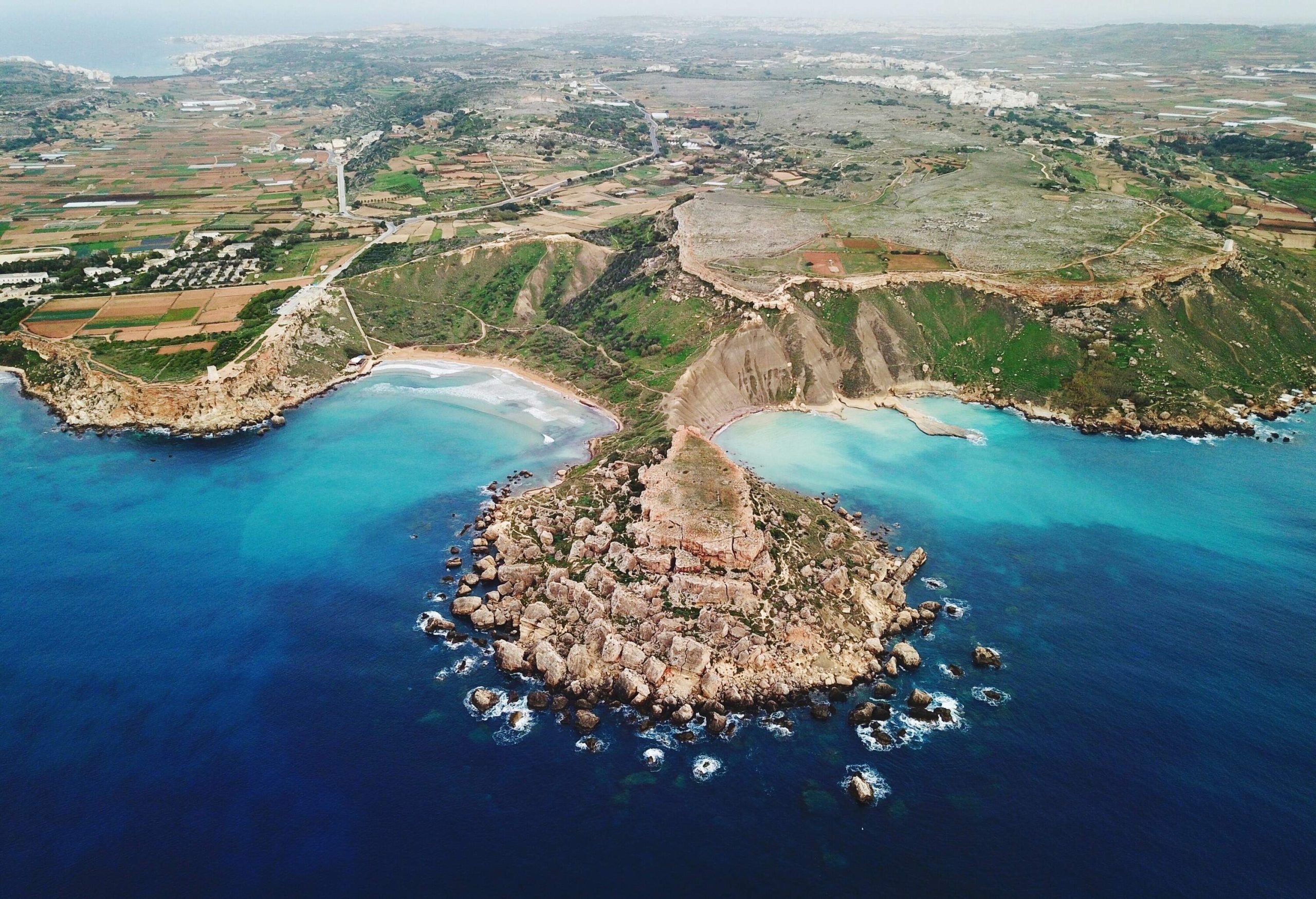 A coastline's edge along a rugged hill with scattered coastal rocks.