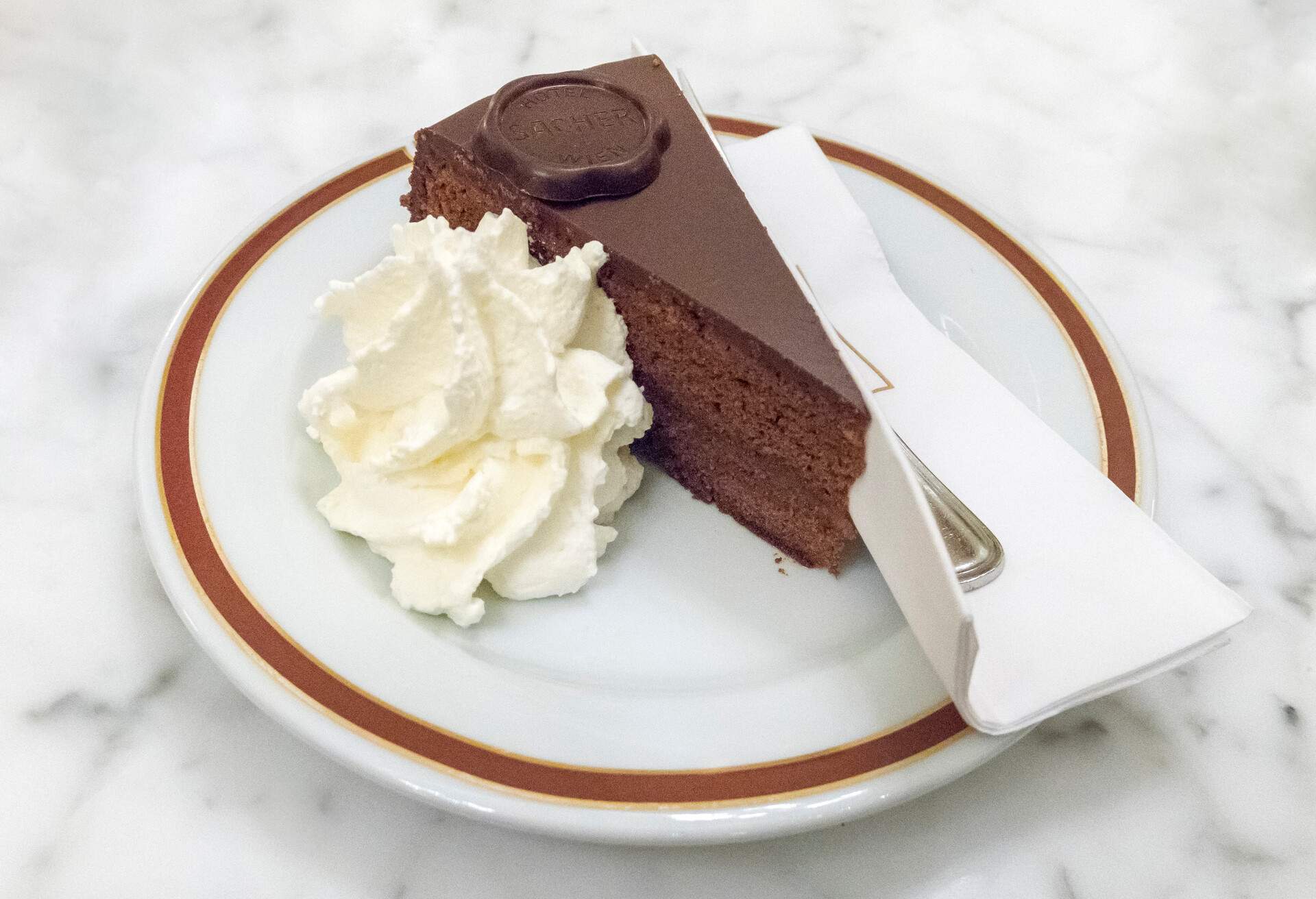 Slice of Sachertorte with whipped cream , at Sacher Hotel pastryshop