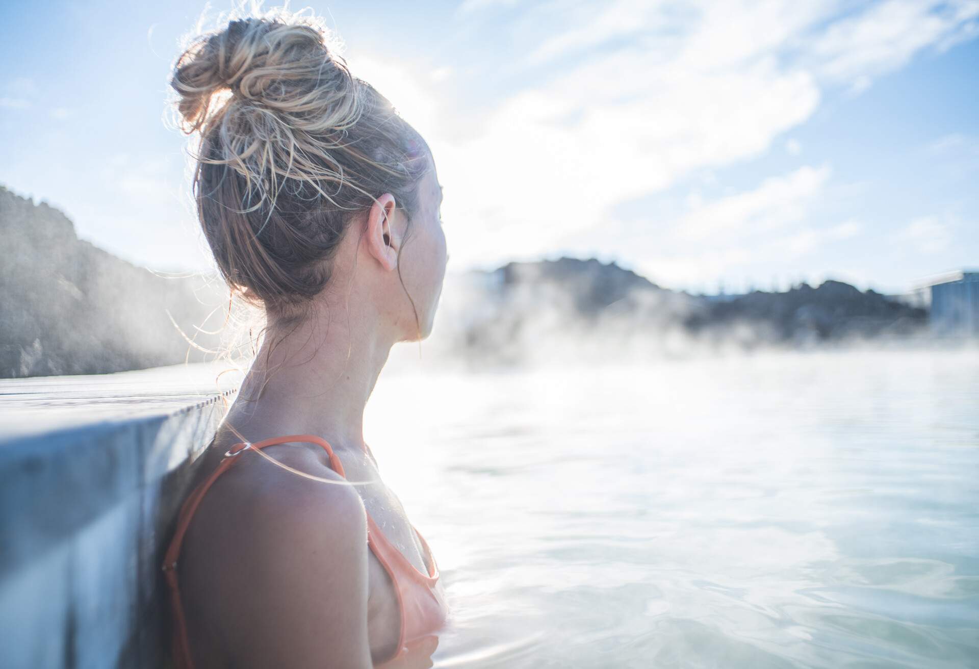 Geothermal spa. Woman relaxing in hot spring pool in Iceland. Girl enjoying bathing in a blue water lagoon Icelandic tourist attraction.