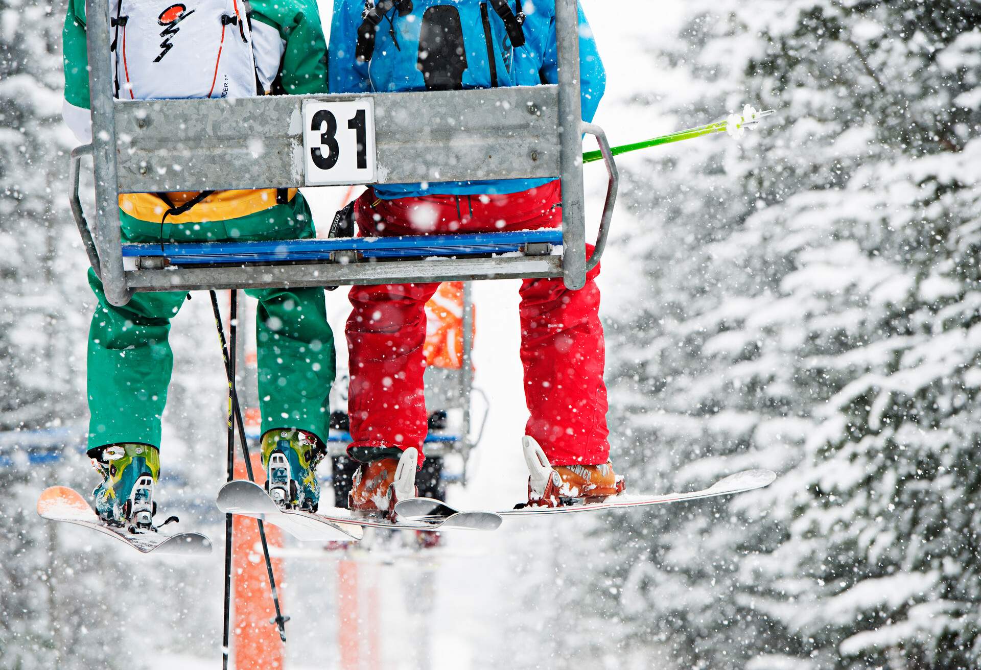 two skiers sitting on a chairlift. heavy snowfall near niseko, japan.