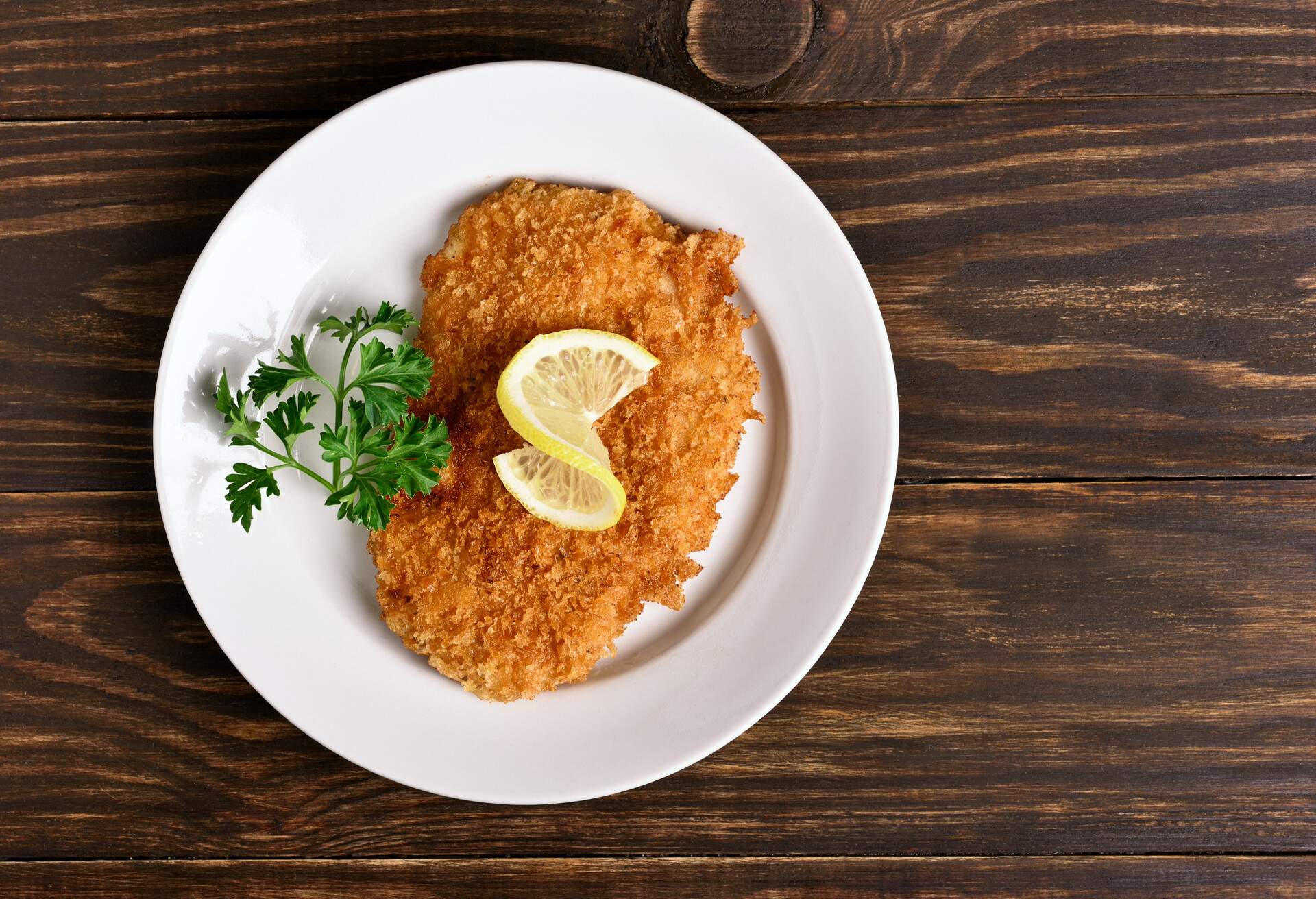 Chicken schnitzel on plate over wooden background, Top view, flat lay
