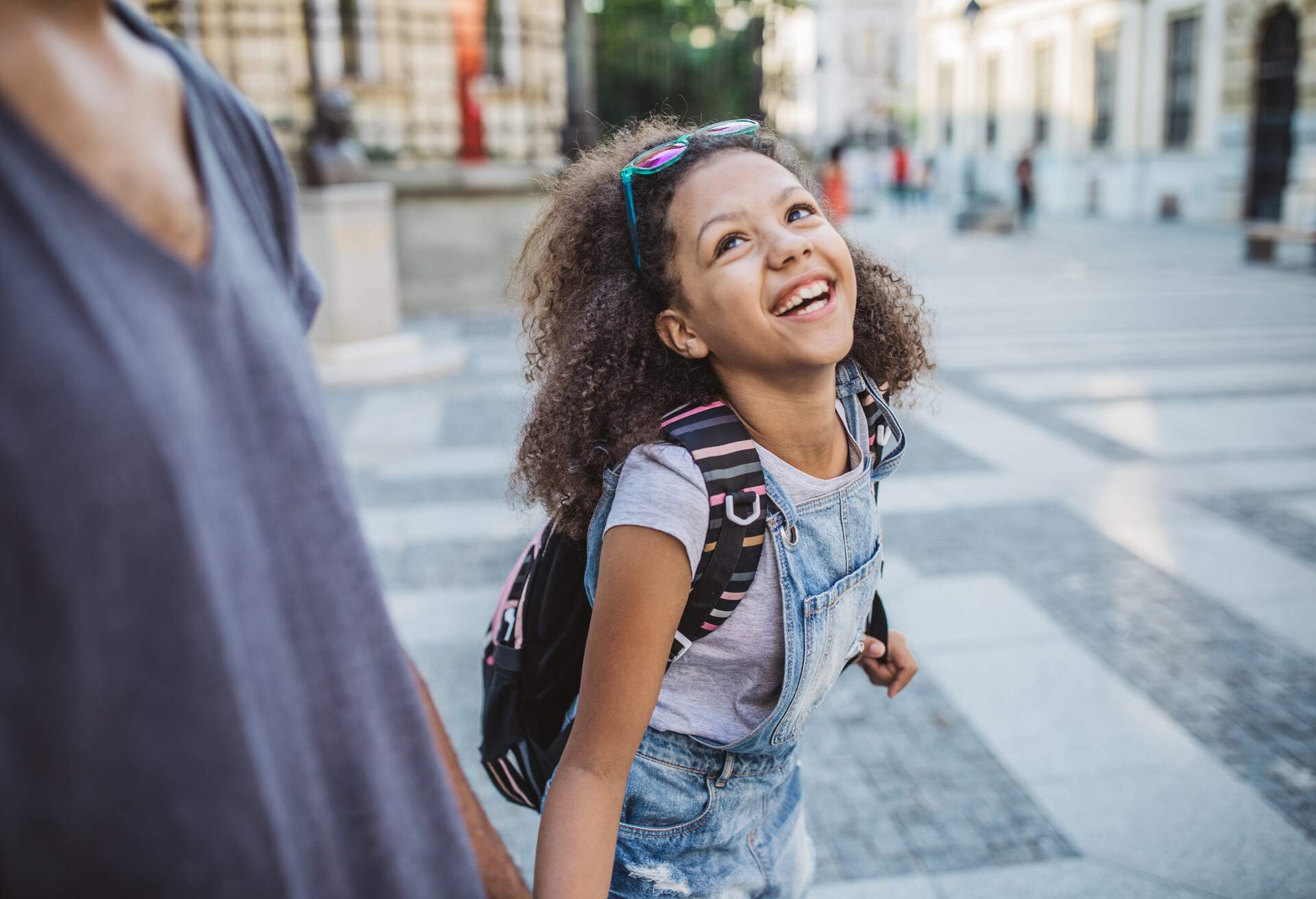 Father bringing daughter to school. Walking the street and holding hands.