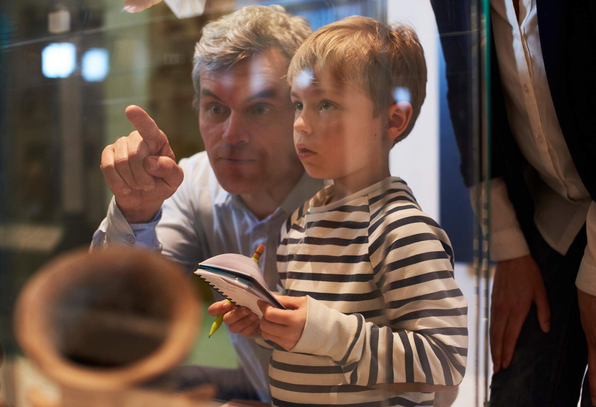 Father And Son Look At Artifacts In Case On Trip To Museum