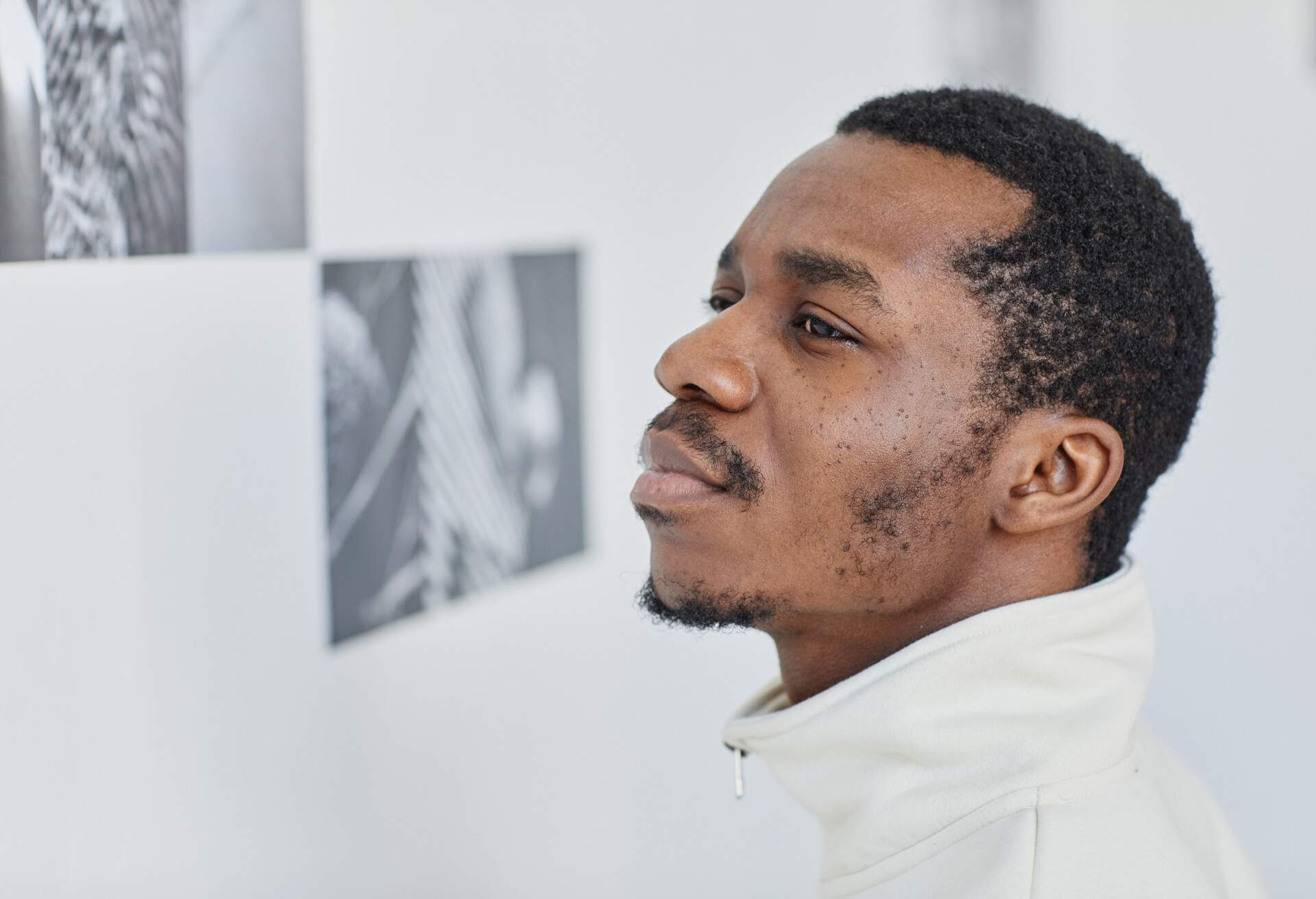 Close up portrait of young black man looking at photographs in art gallery, copy space