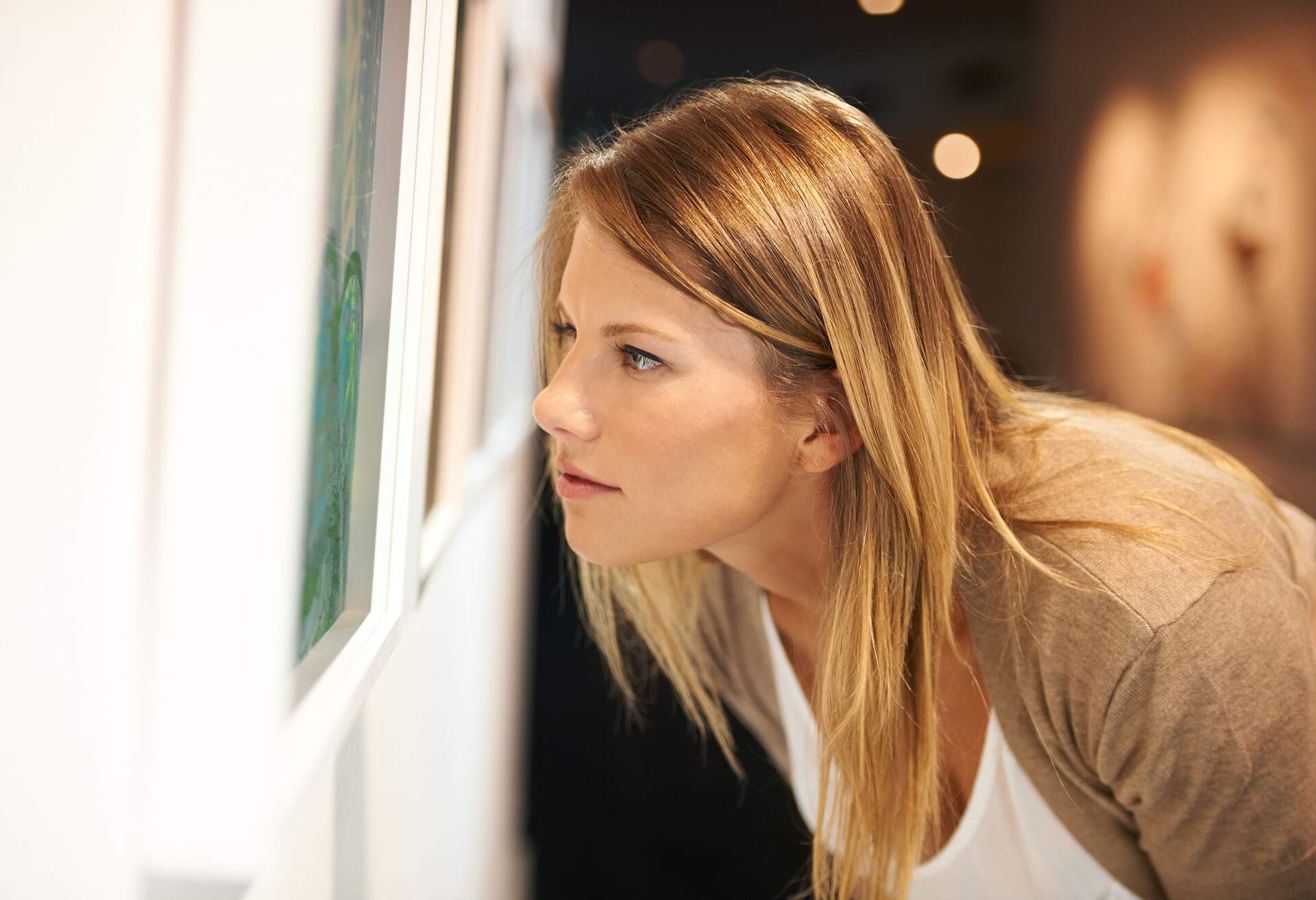 A woman leaning forward and closely examining a picture.