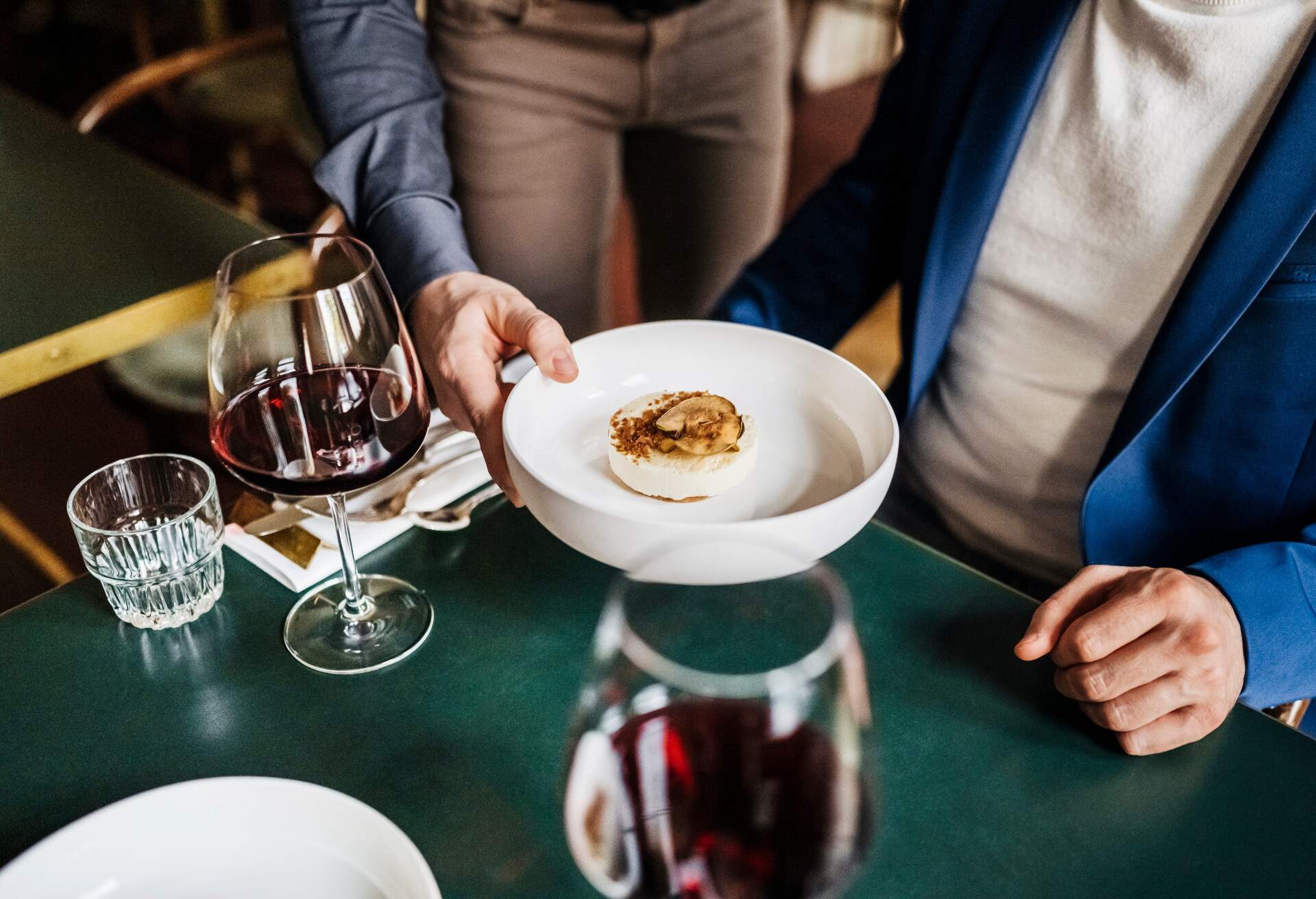 A close up of a waiter serving a customer his starter dish at a luxurious restaurant 