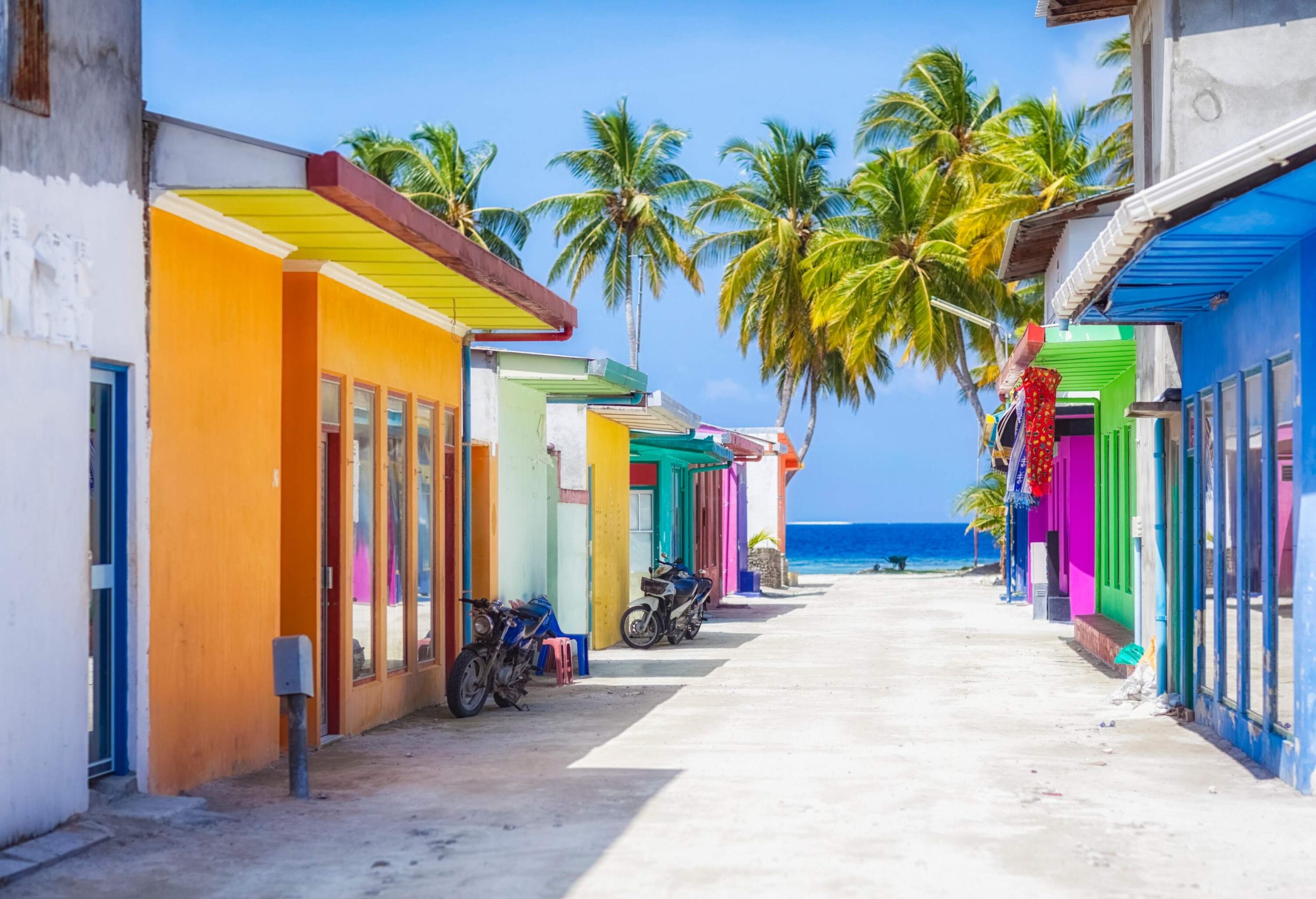 A coastal village with vibrantly painted houses along the street that opens up to the sea.